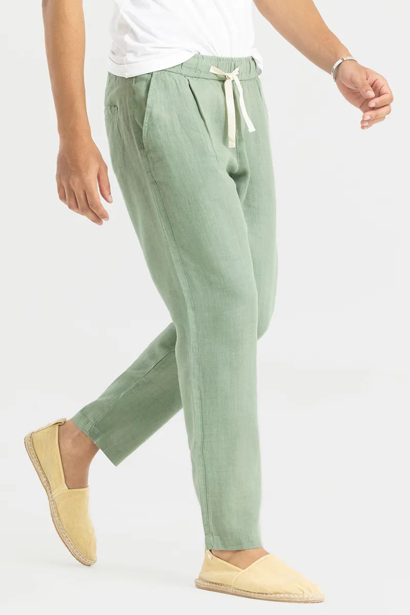Side view of a man mid-stride, showcasing the relaxed fit and light fabric of pista green cotton linen pants.