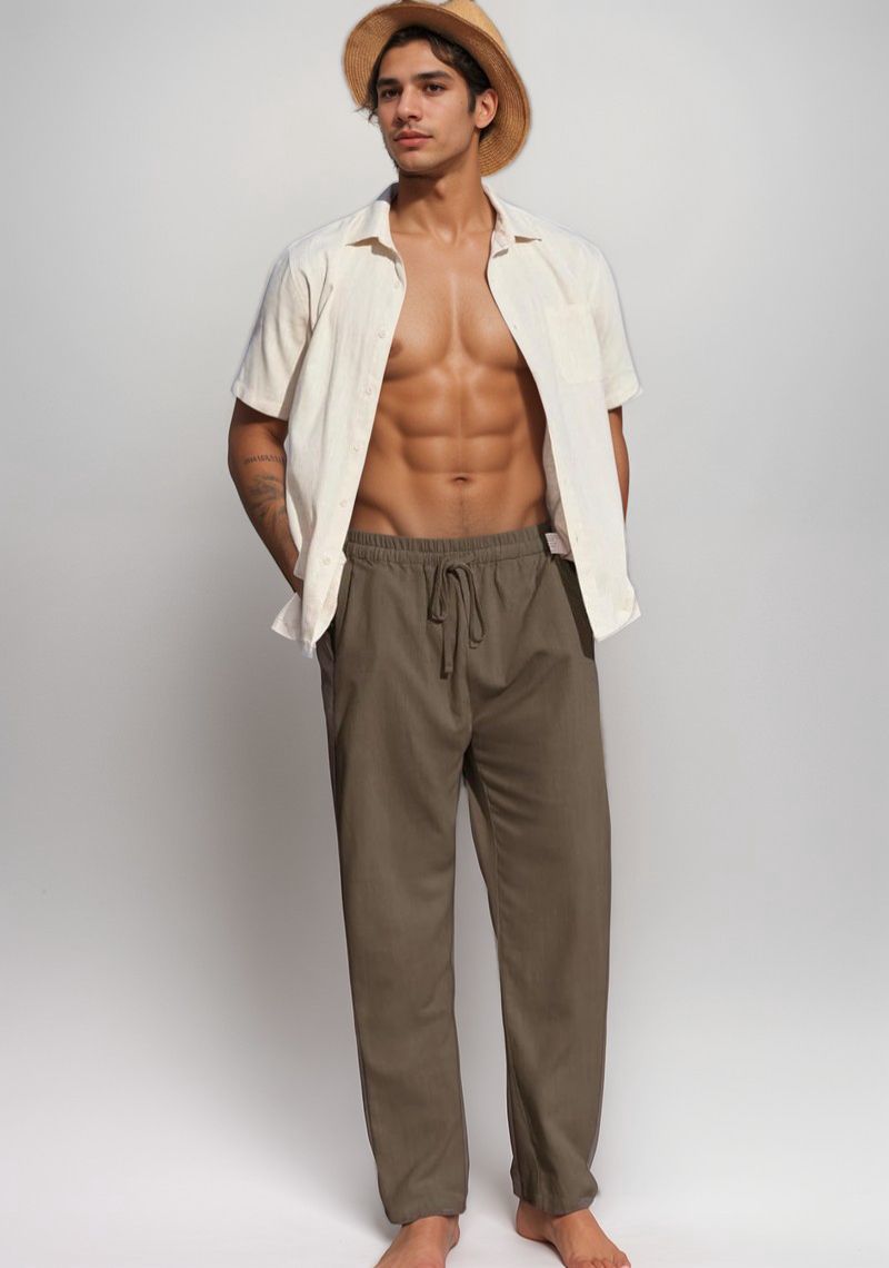 A fit man in a straw hat and open cream shirt, posing confidently in military green cotton linen pants.