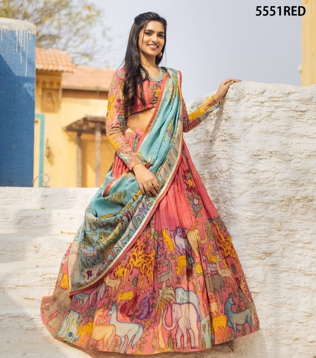 Model smiling in a vibrant red Kalamkari printed lehenga choli with a light blue dupatta, showcasing the intricate design.