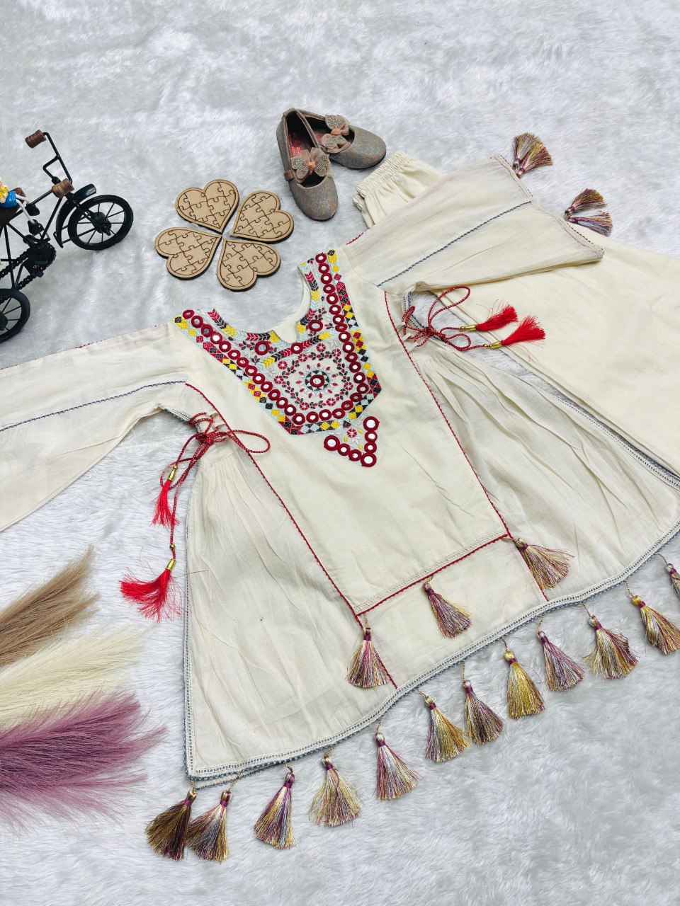 Overhead view of khadi cotton plazzo set on a white textured surface, highlighting intricate embroidery and tassels.