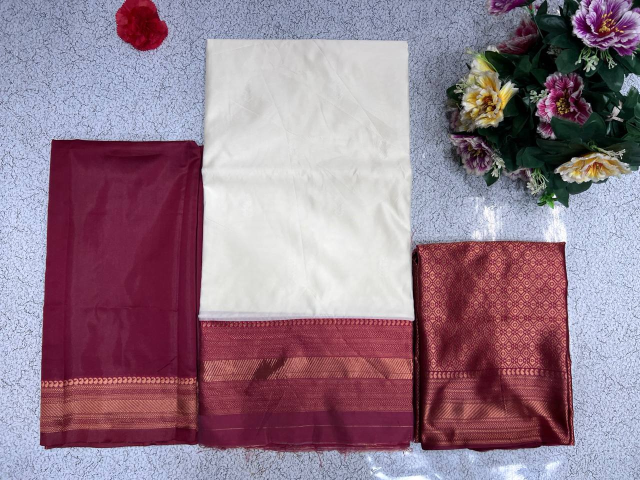 Flat lay of TRENDBUY Kanjiveram Silk half saree lehenga fabric set in maroon: cream lehenga, maroon blouse piece, and banarasi voni.