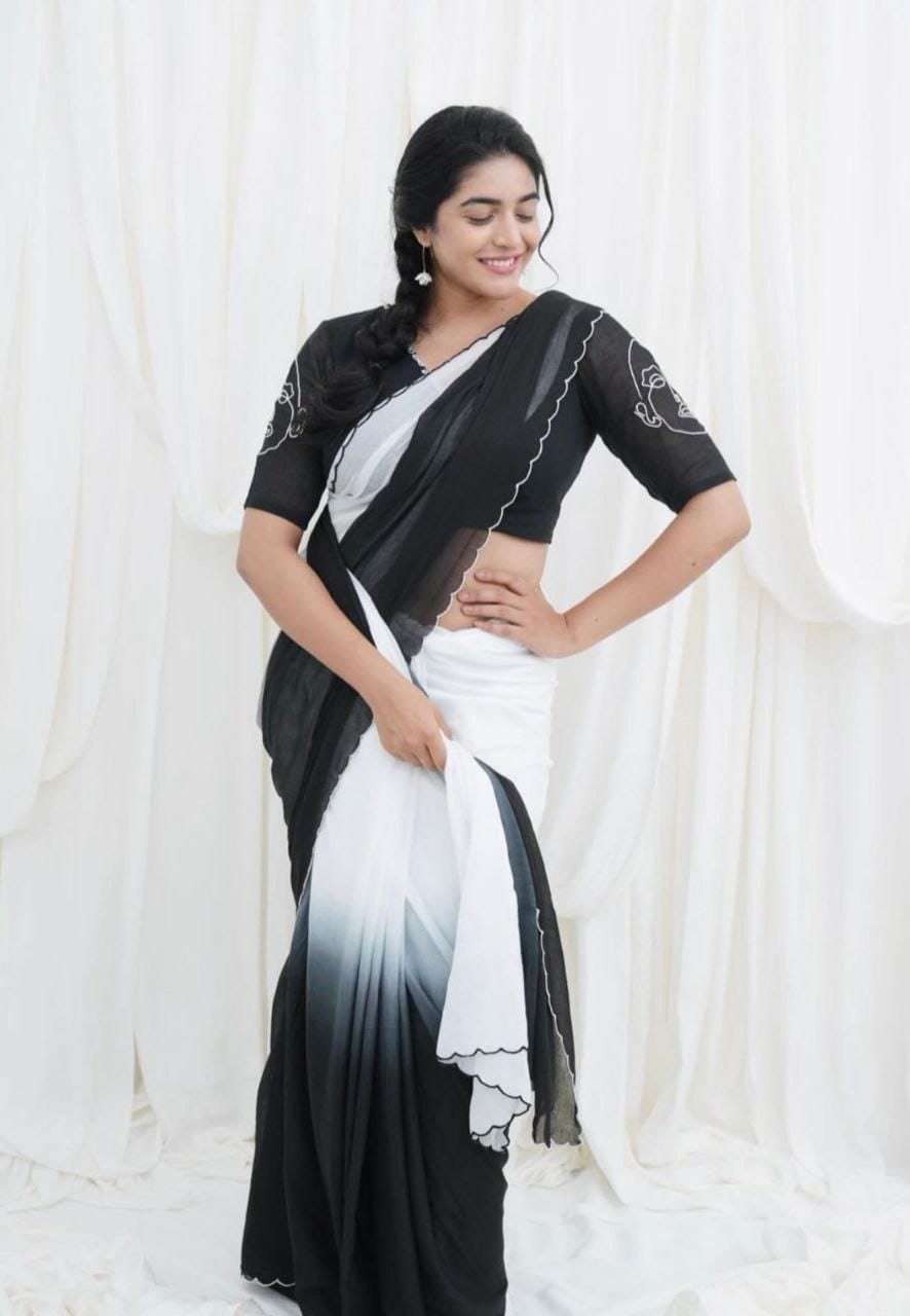 Model gracefully posing in a black and white ombre linen saree with an artistic abstract face print blouse.