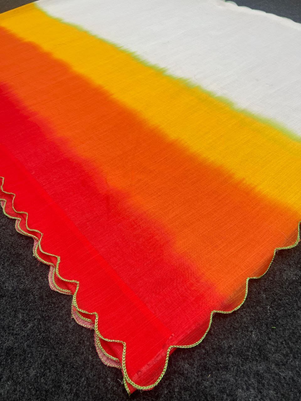 Close-up detail of the multi-color sunset ombre linen fabric with a delicate green scalloped cut work border.