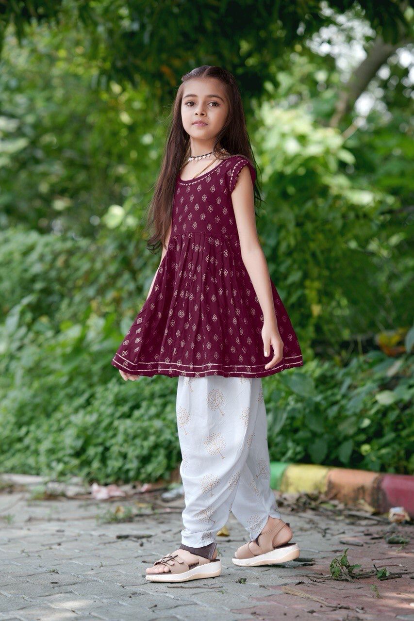 Girl twirling in the maroon foil print kurti and dhoti patiala set