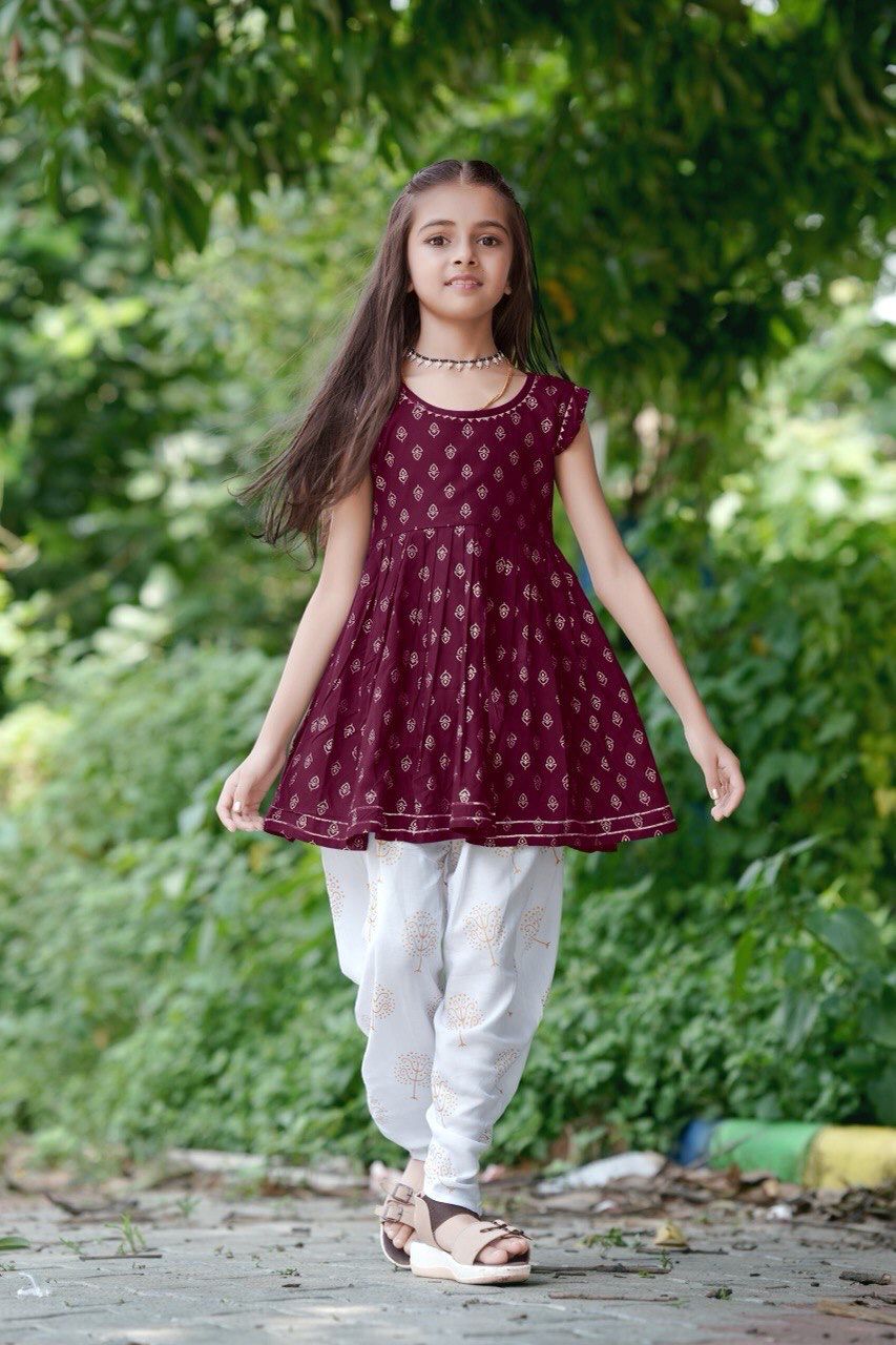 Girl twirling in the maroon foil print kurti and dhoti patiala set