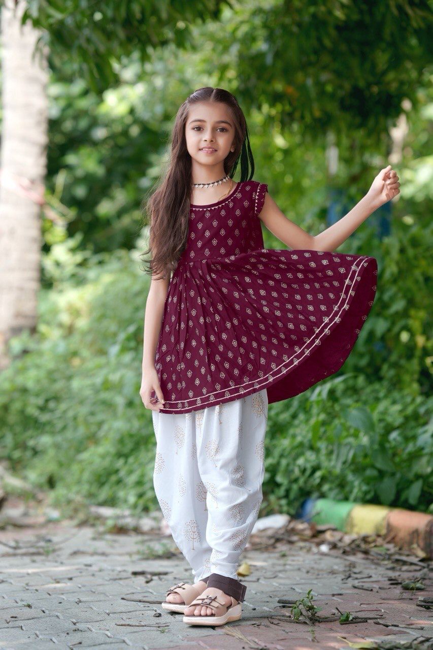 Girl twirling in the maroon foil print kurti and dhoti patiala set