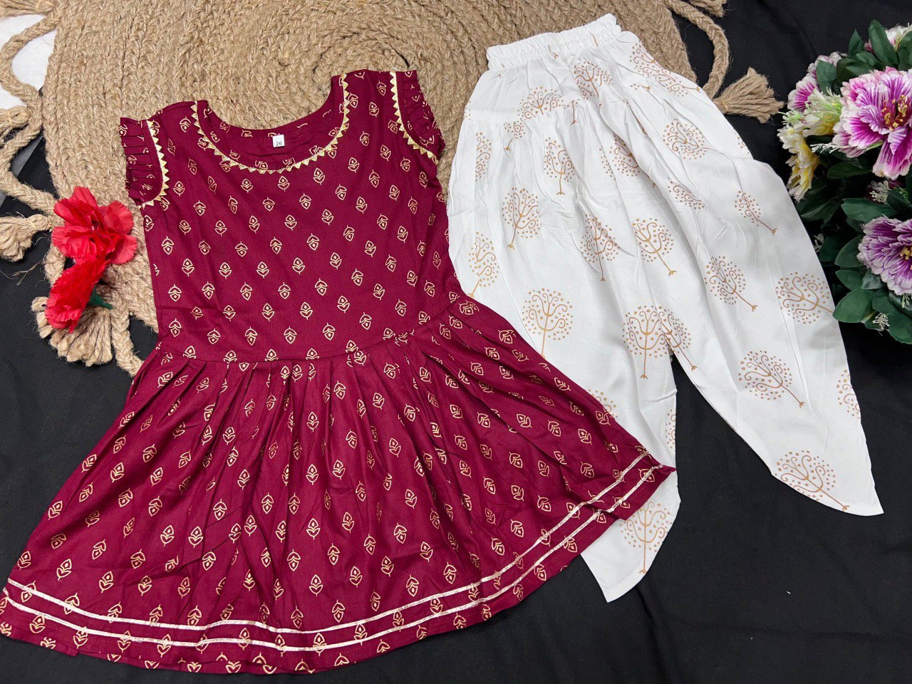 Red and white traditional outfit with floral patterns on a dark surface.