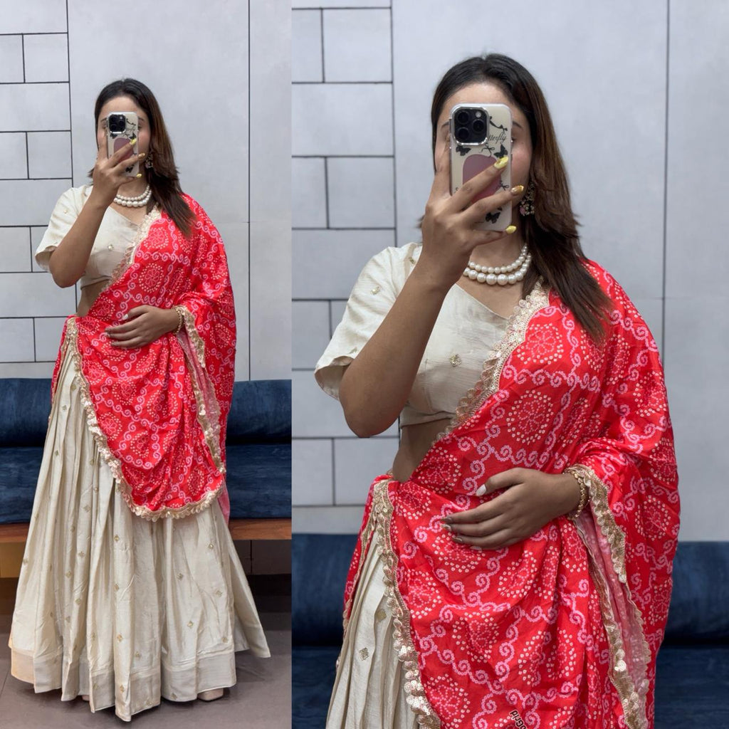 Model wearing the off-white Chinnon silk lehenga with a traditional red Bandhani dupatta