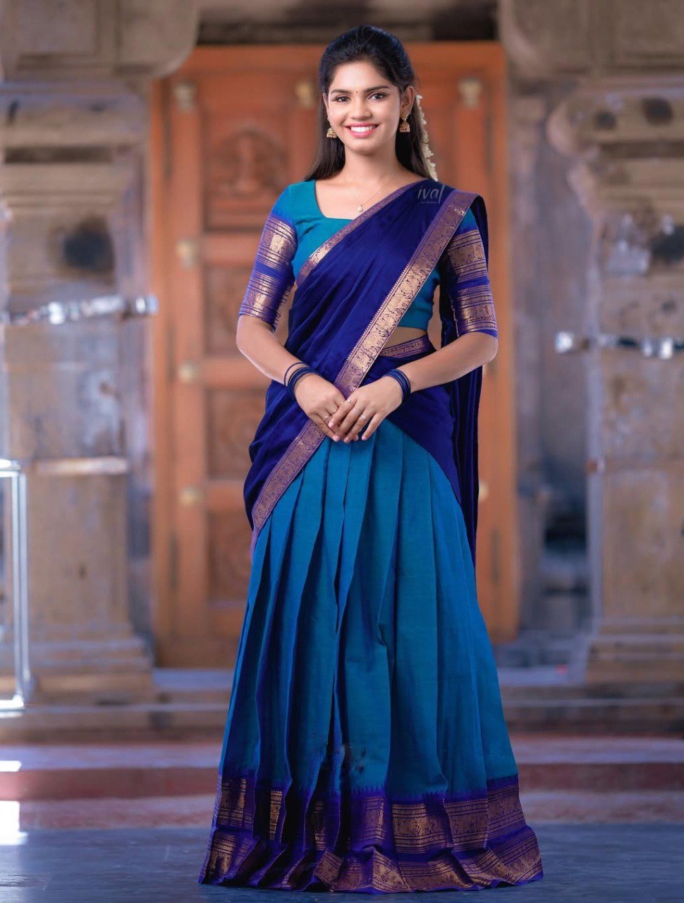 Woman wearing a blue saree with a matching blouse in an indoor setting