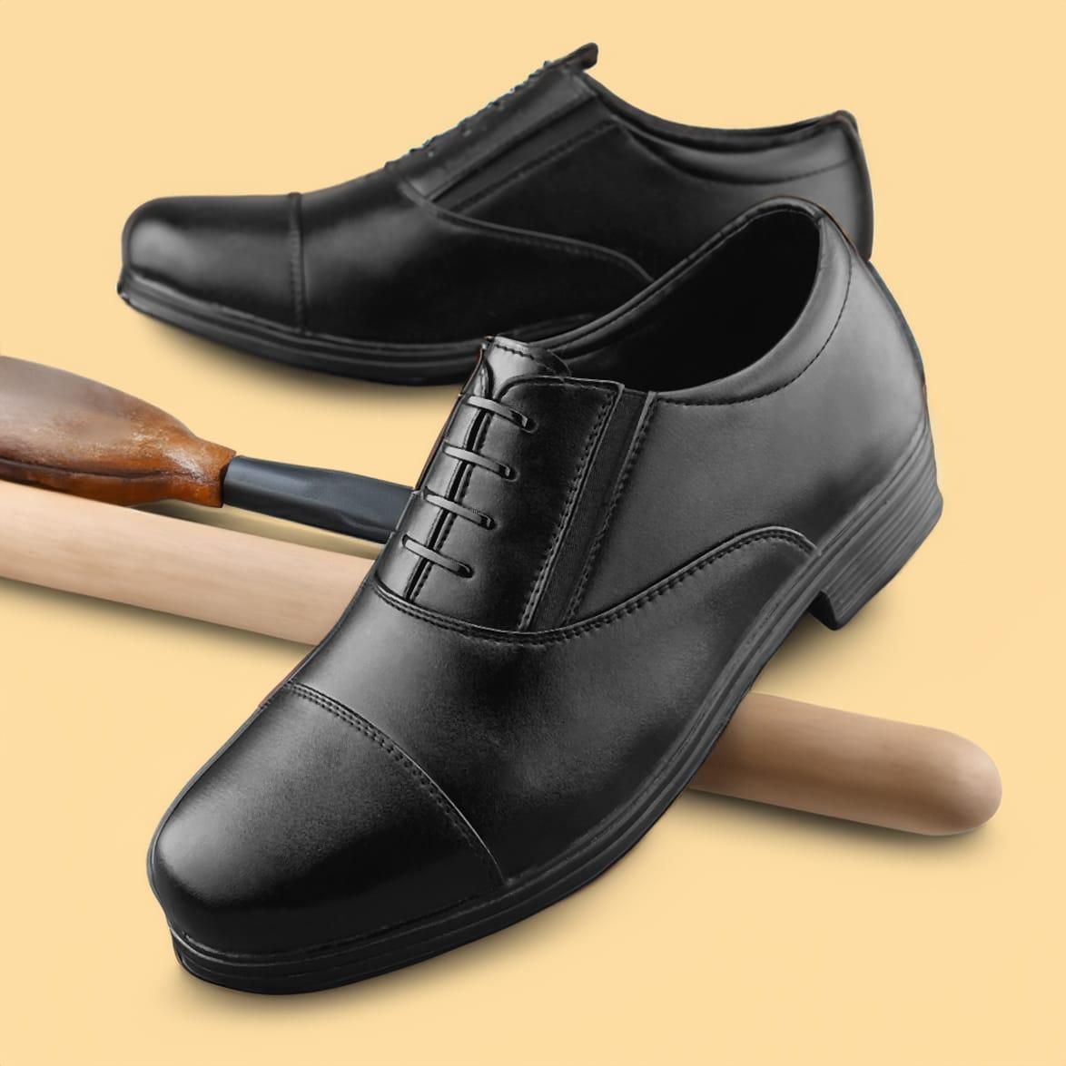 Black dress shoes on a beige background with a wooden broom.