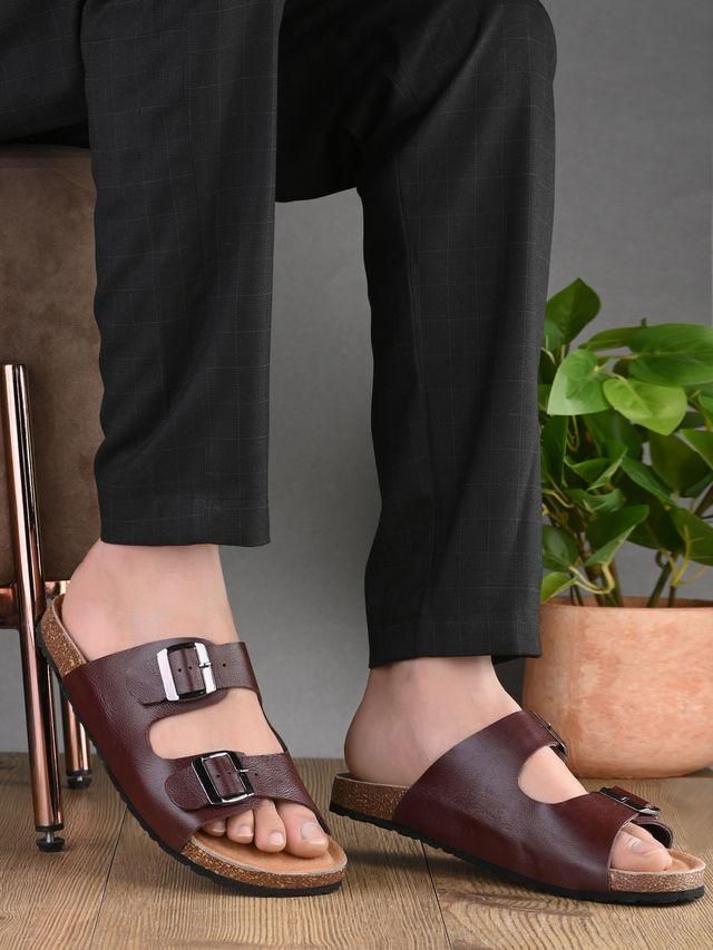 Brown sandals worn with black pants on a neutral background