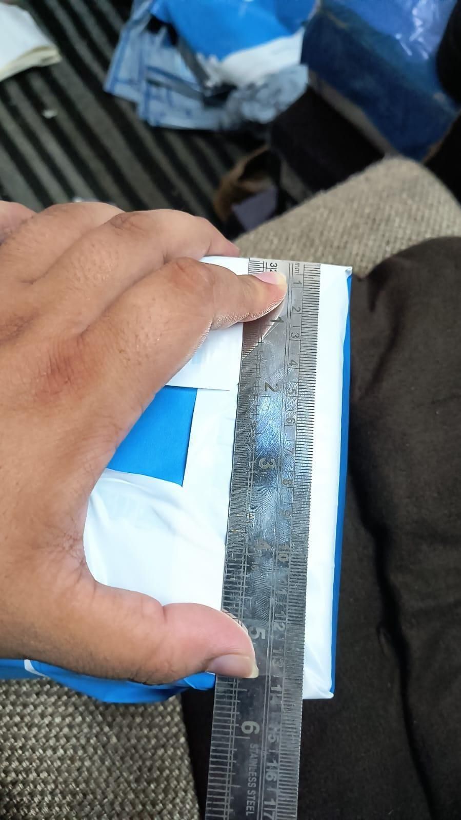 Hand holding a ruler over a box with blue tape
