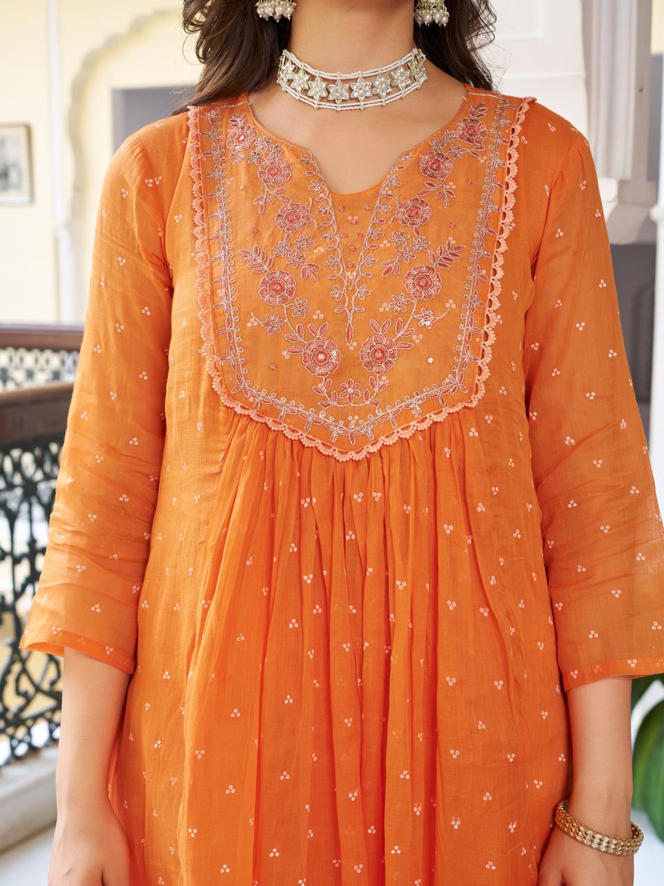 Detailed close-up of the orange kurti's embroidered V-neckline and gathered bust design, showcasing the fabric texture and craftsmanship.