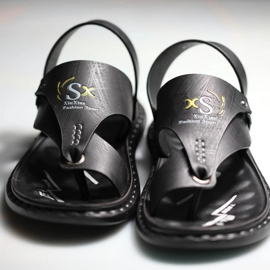 Black sandals with 'XS' logo on a light gray background