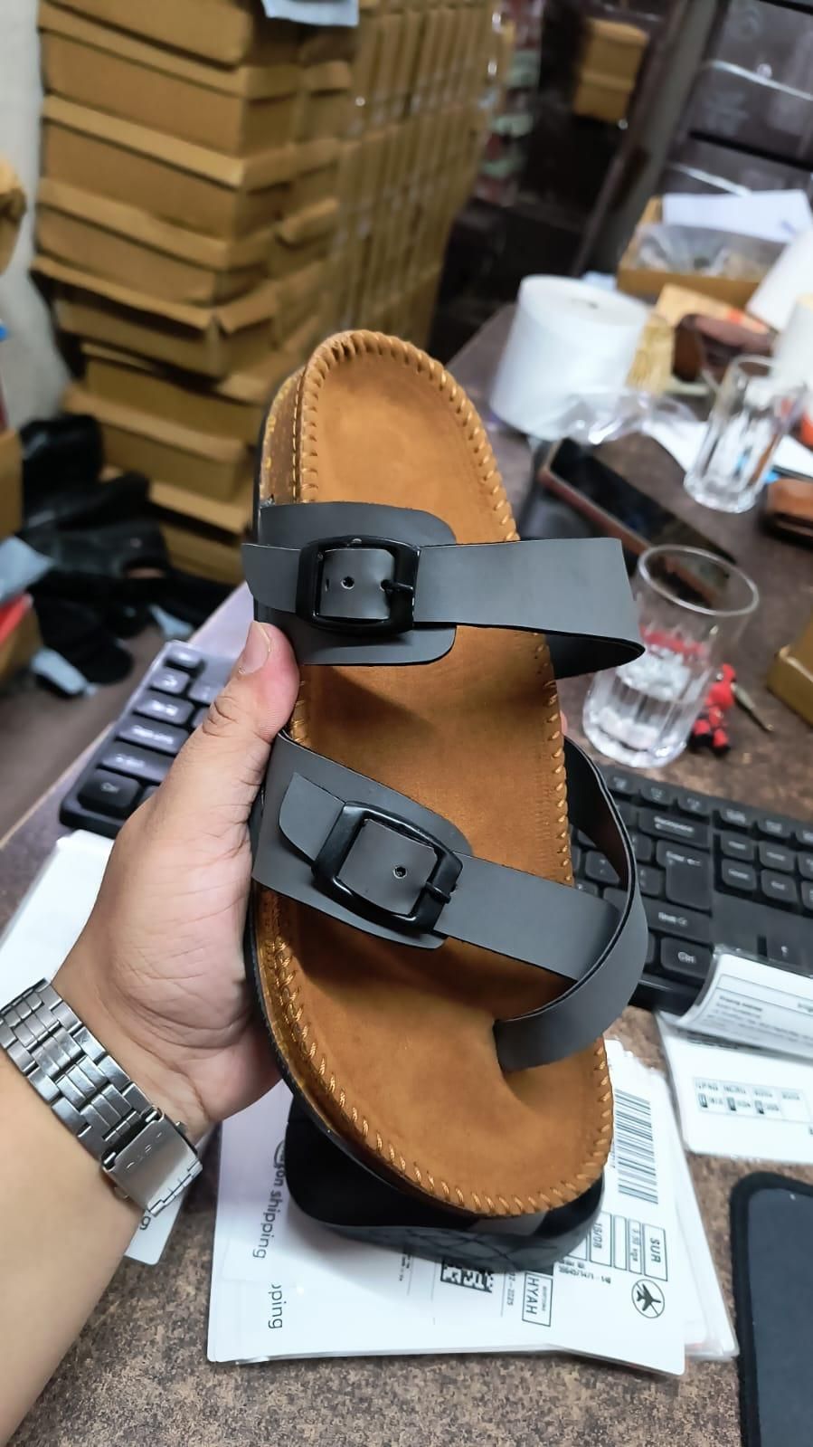 Person holding a sandal with black strap in a store setting