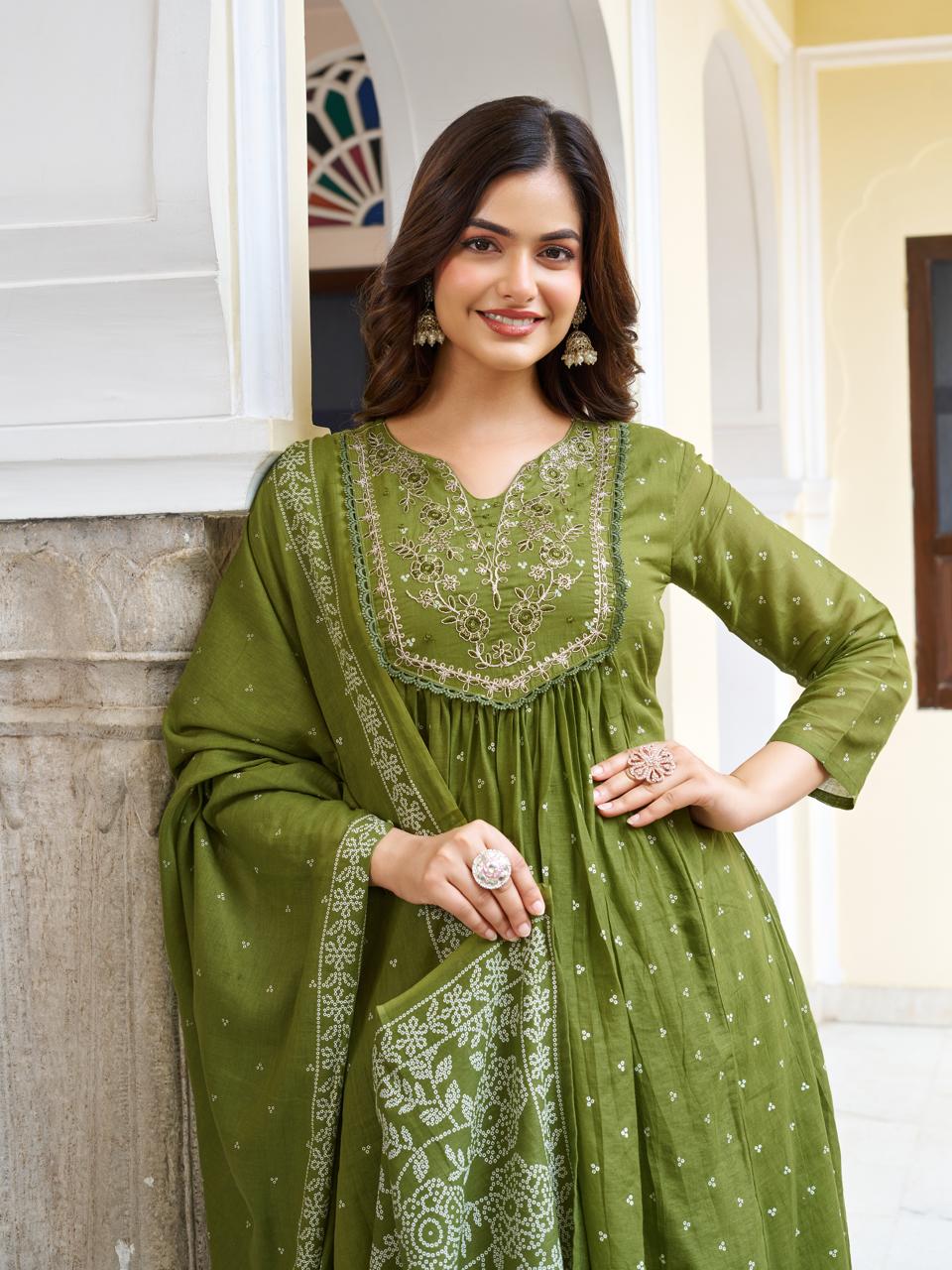 Close-up of a smiling model in an olive green kurti set, highlighting her radiant face, jewelry, and the intricate embroidery on the kurti's neckline.