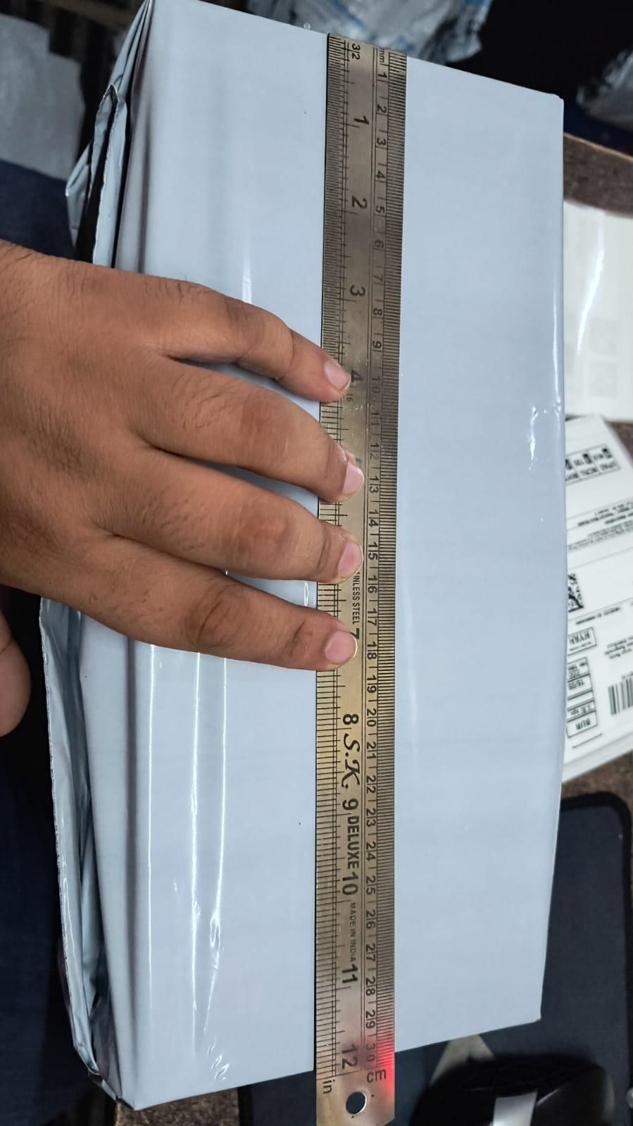Hand holding a ruler over a stack of white sheets with a blurred background