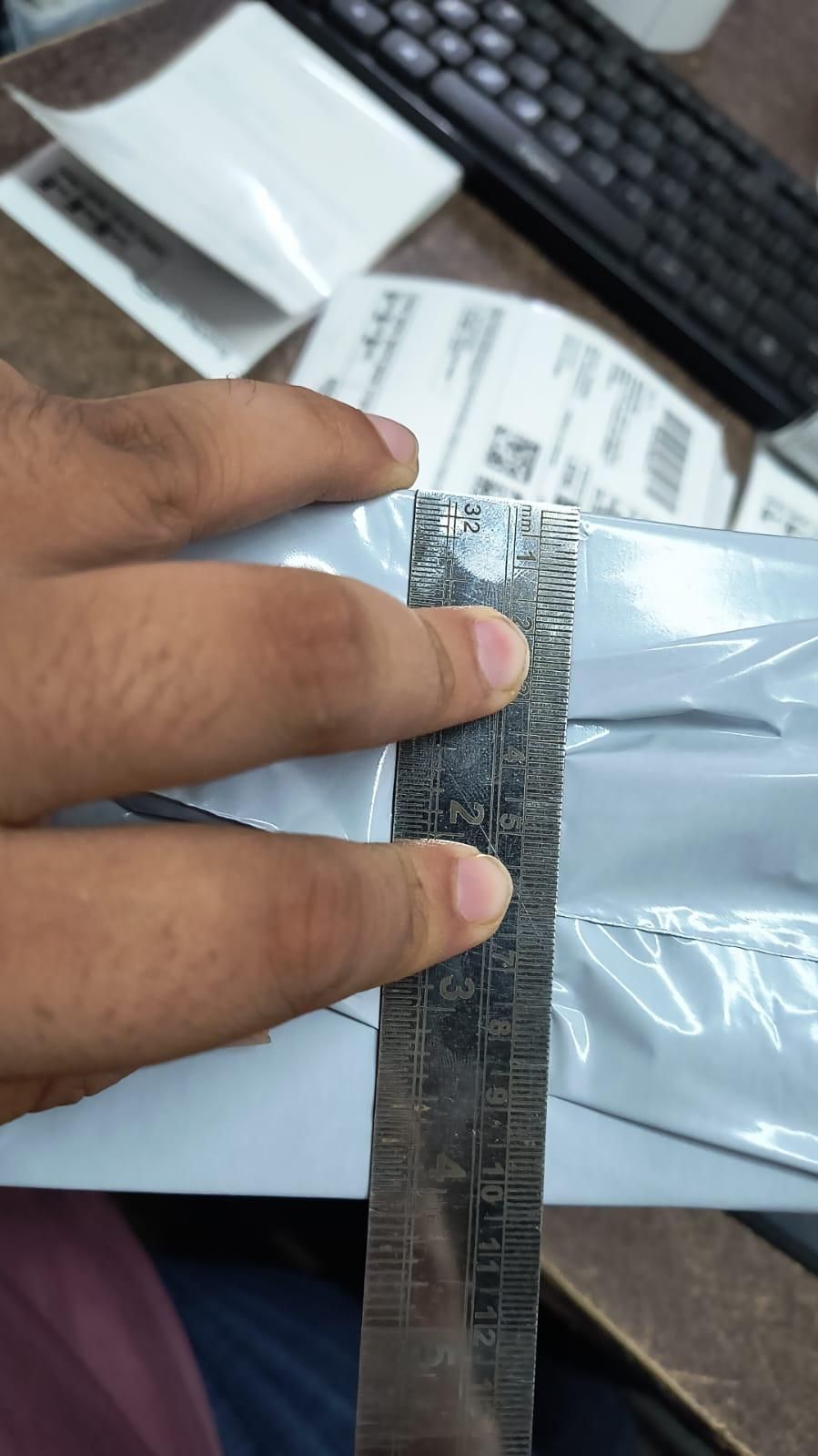 Hand holding a ruler over a small object with a blurred background