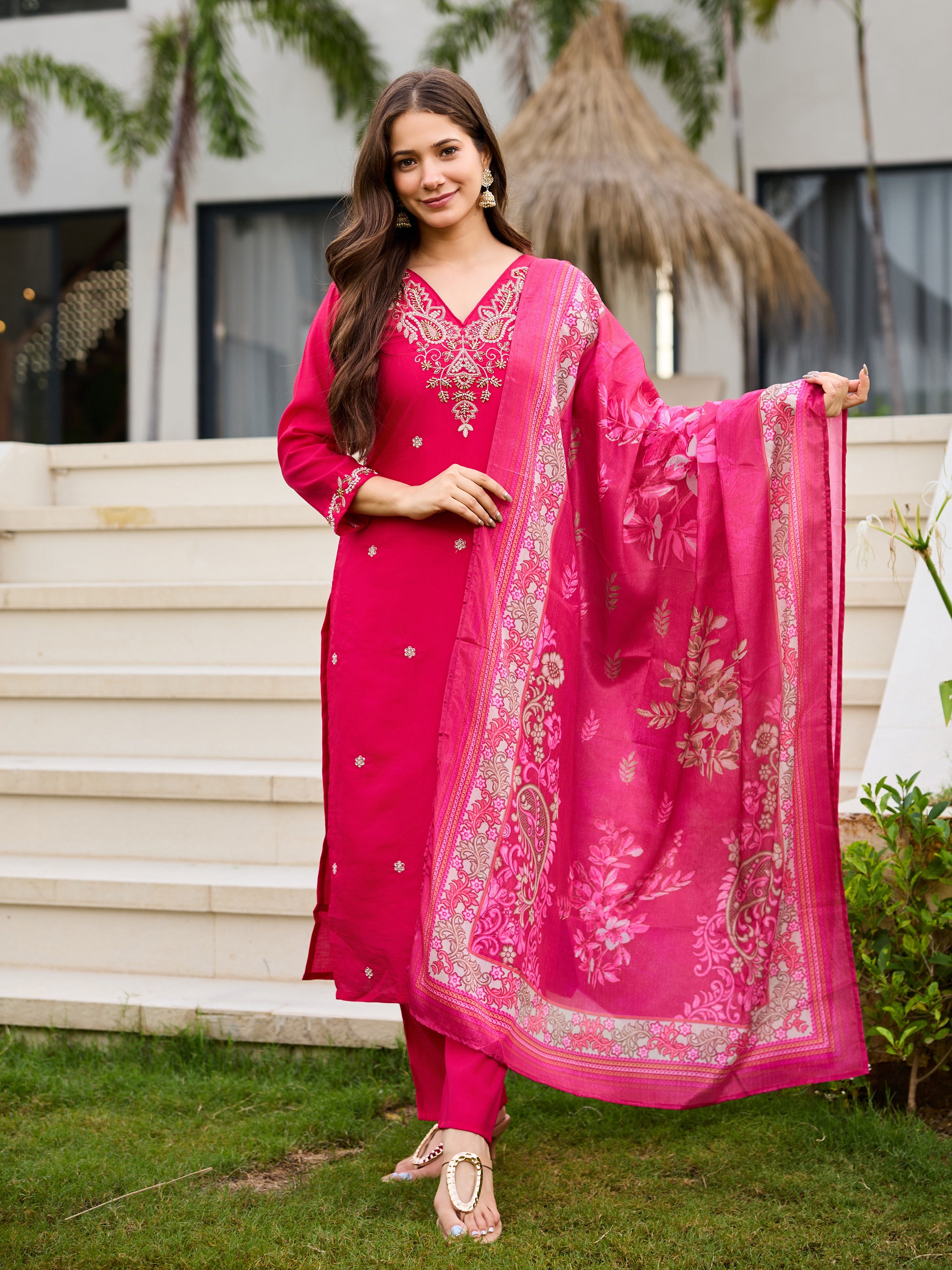 Woman in pink kurti set, gracefully holding the heavy chinnon floral print dupatta draped over one arm, outdoors.
