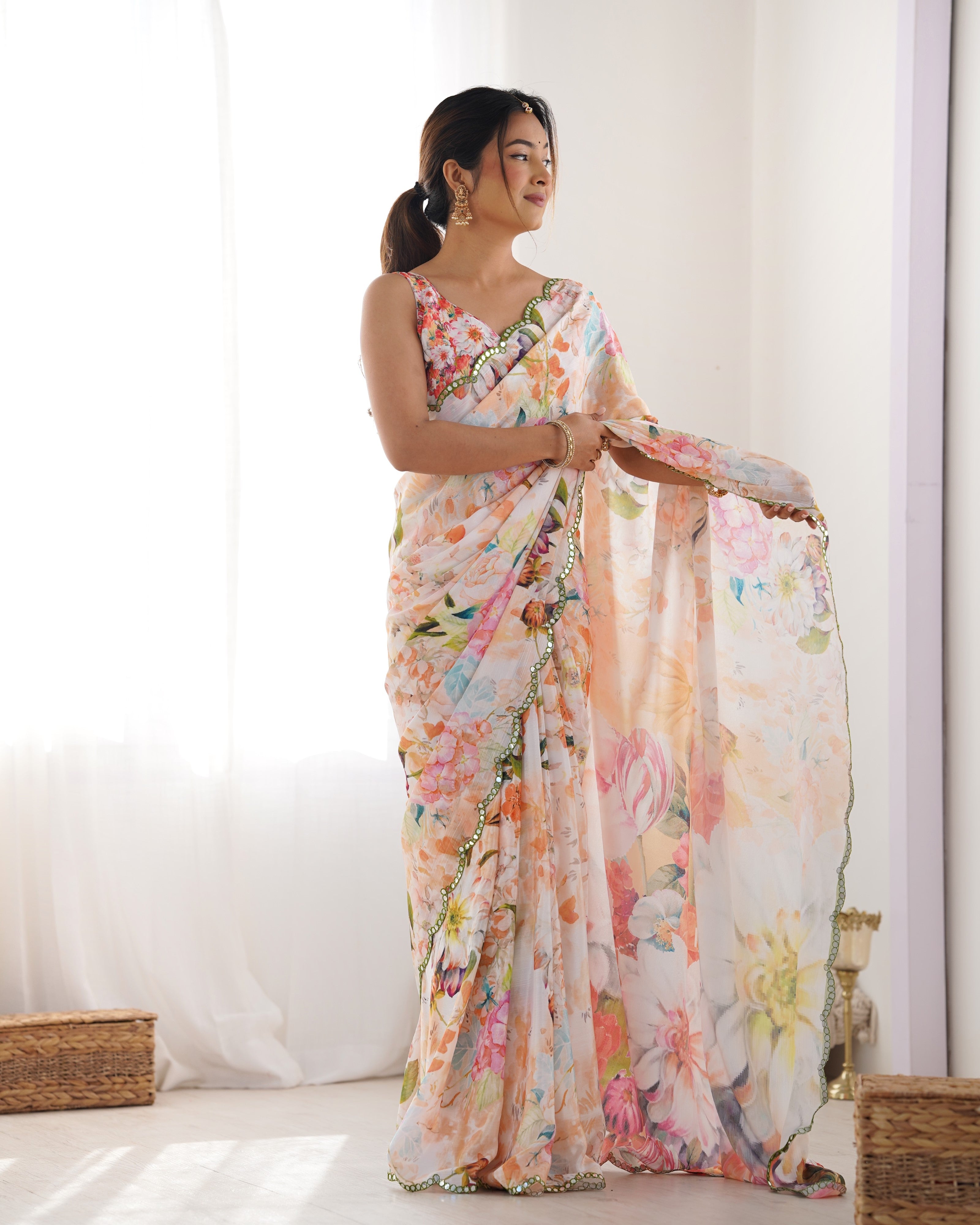 Model adjusting her beautiful printed chinnon saree, highlighting its flow and the delicate mirror border.