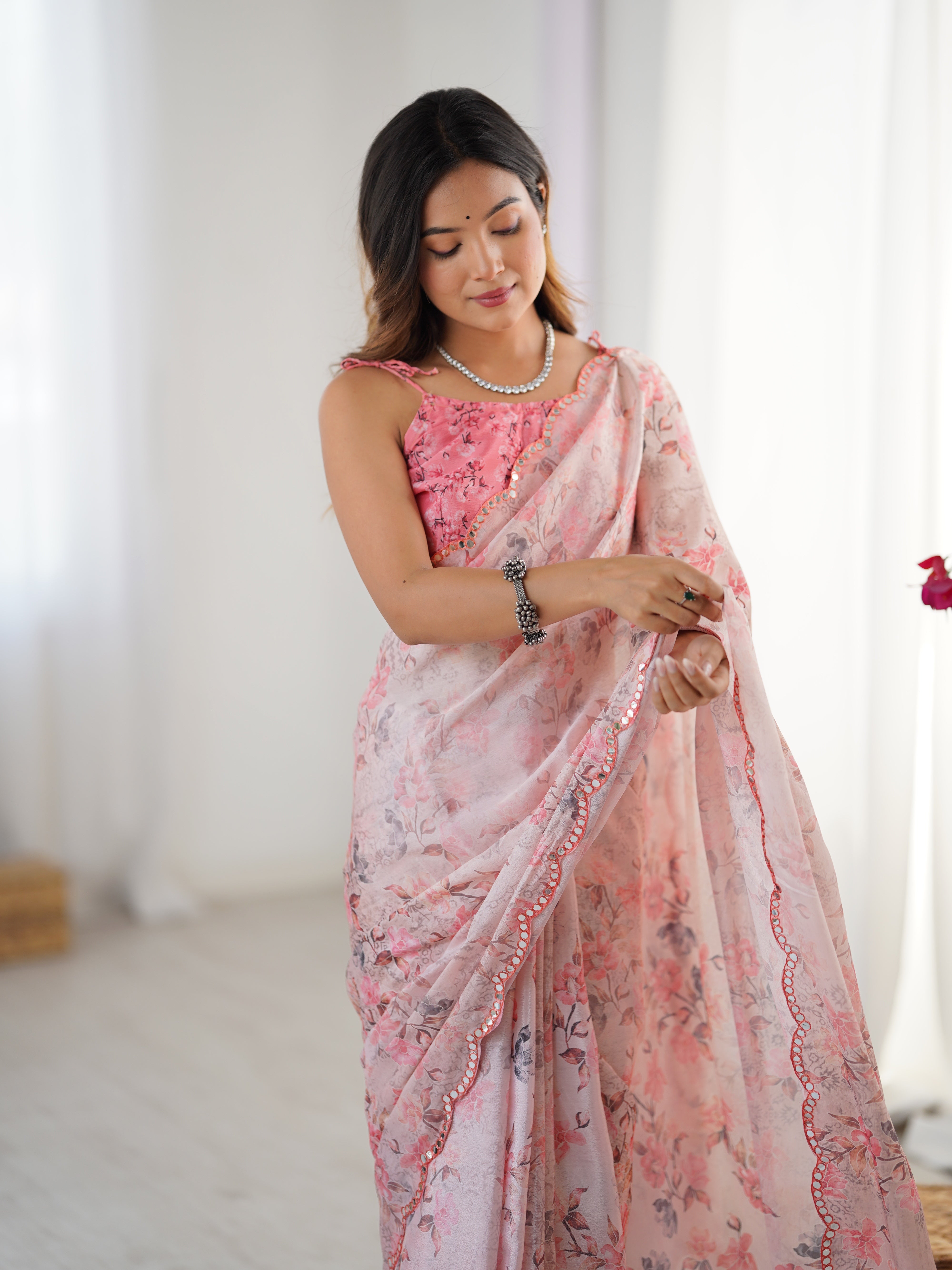 Model looking down gracefully, emphasizing the flow and design of the pink floral chinnon saree with unstitched blouse.