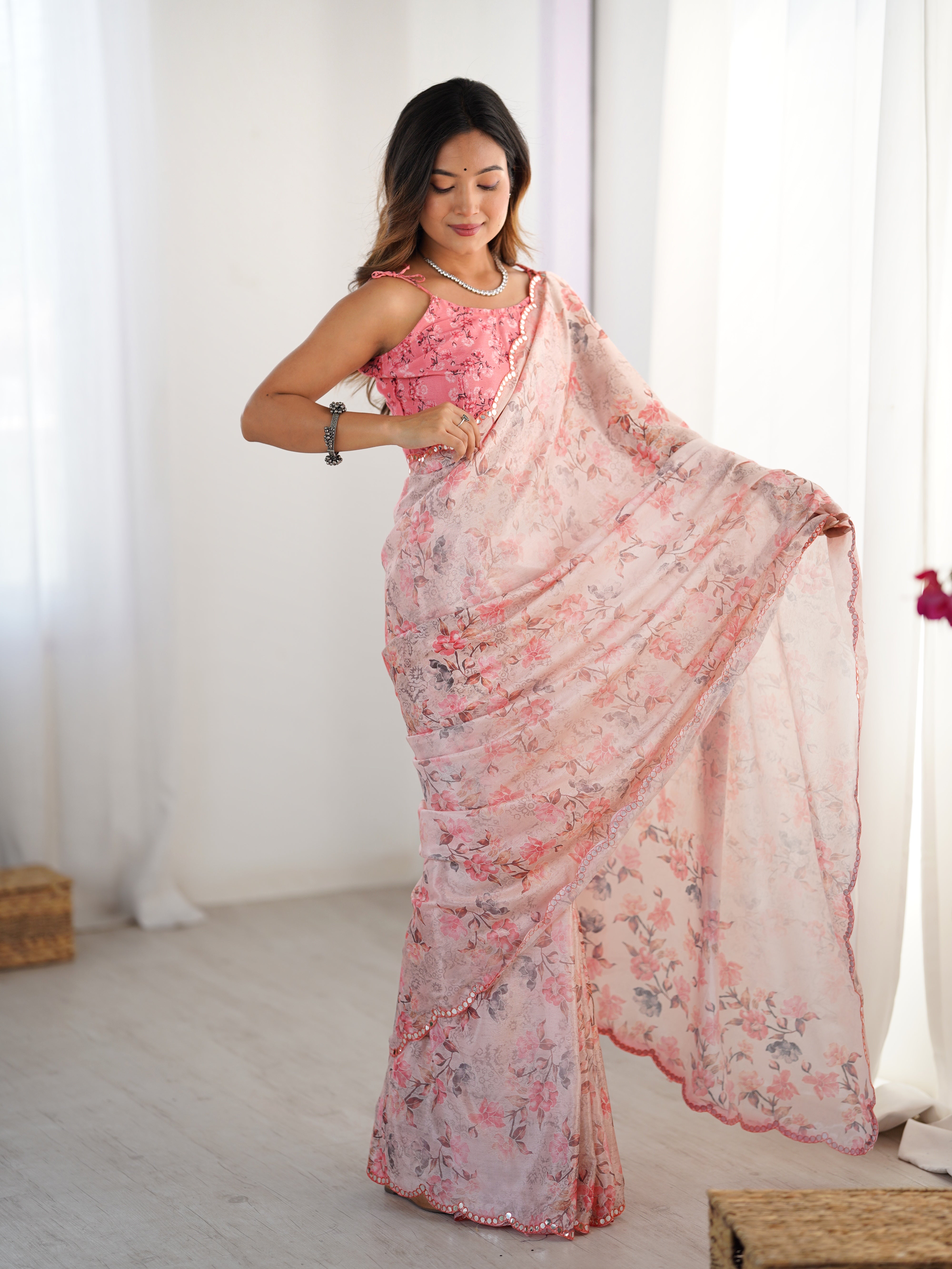 Model twirling slightly, displaying the full breadth and intricate mirror work of the heavy chinnon floral print saree.