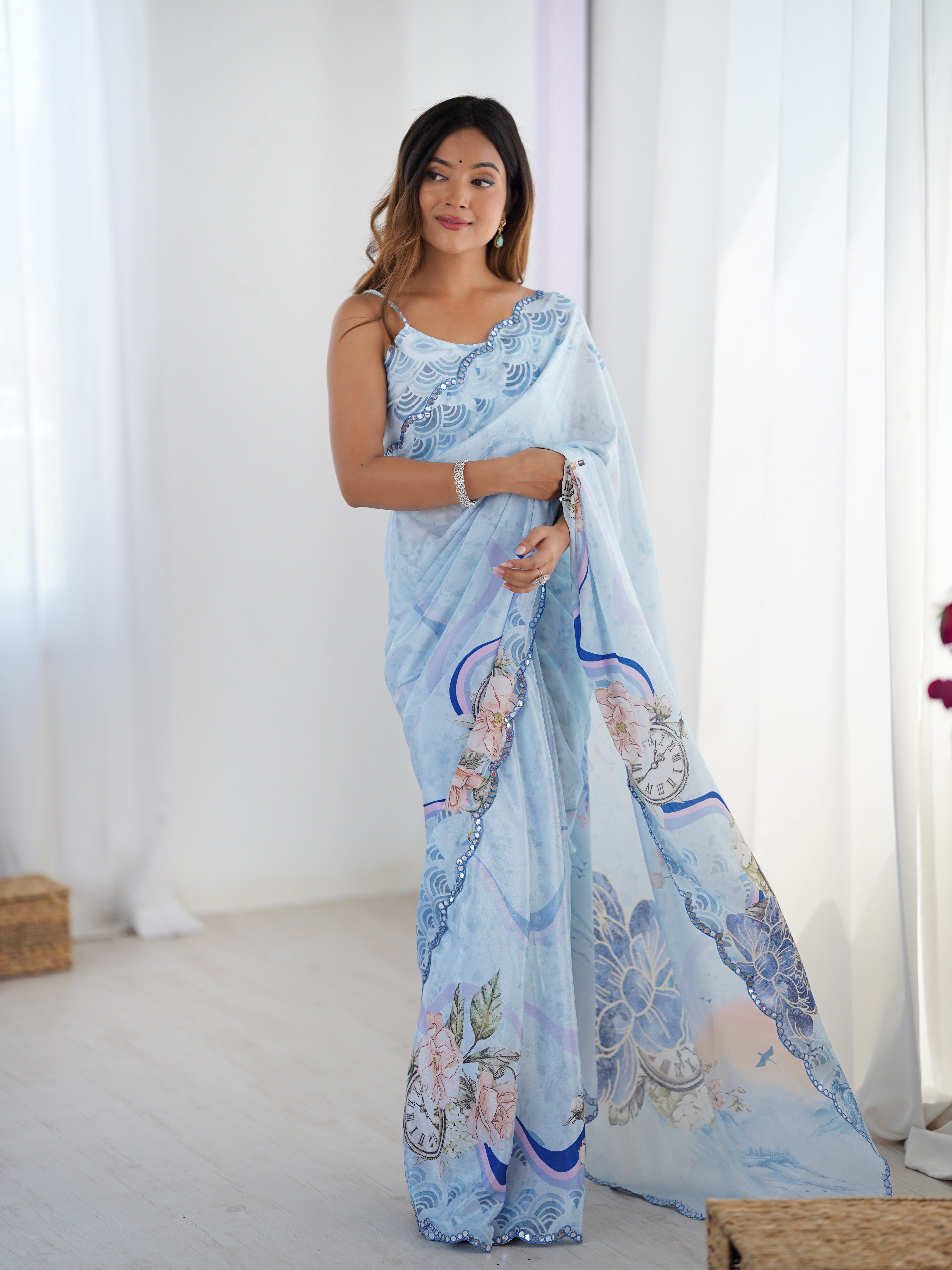 Smiling model gracefully posing in a sky blue heavy Chinnon saree with Kutchi mirror work border by TRENDBUY, showcasing the pallu and blouse.