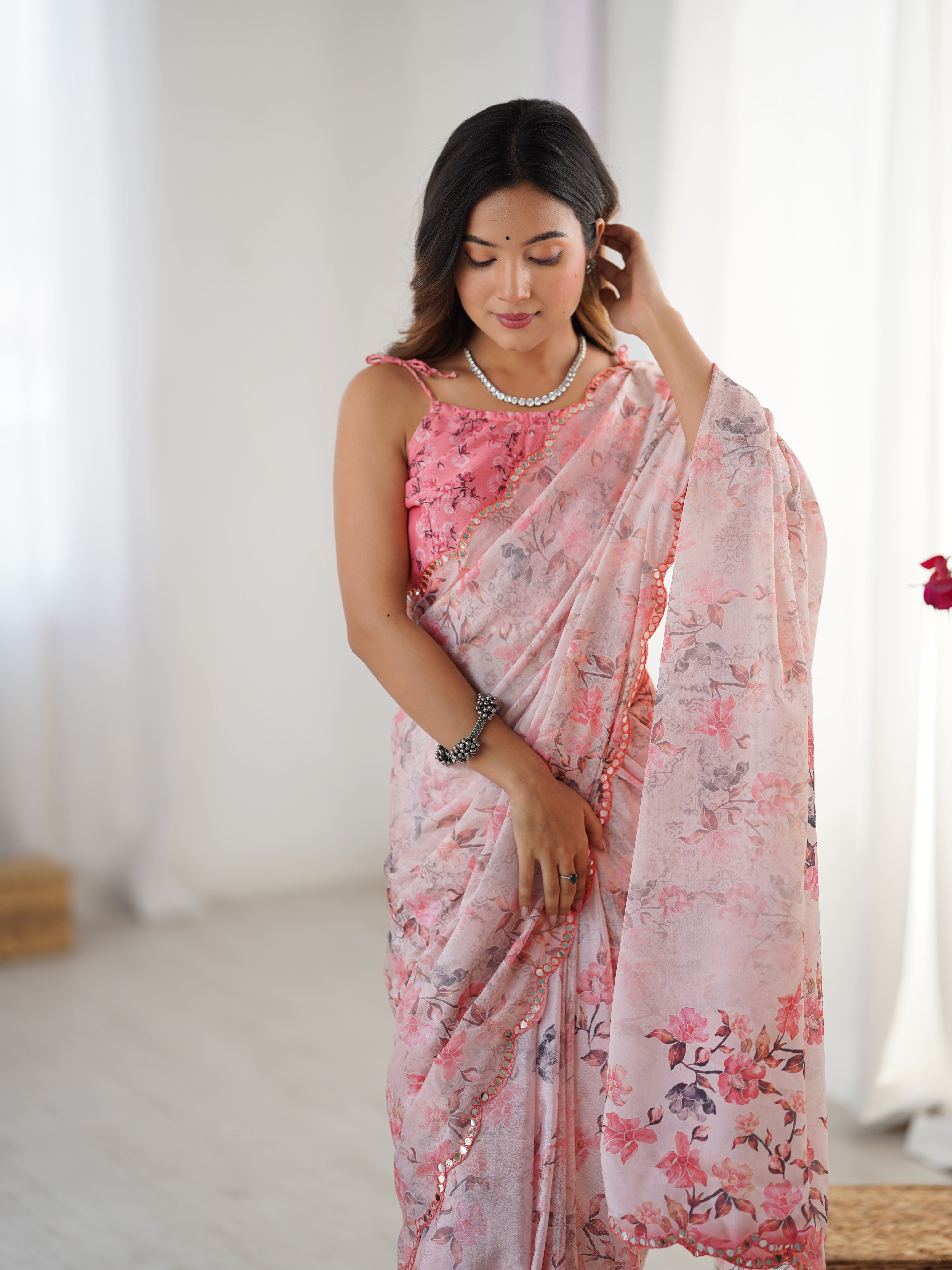 Stylish model gently touching her hair while presenting the soft, flowing fabric and stunning floral design of the TRENDBUY saree.