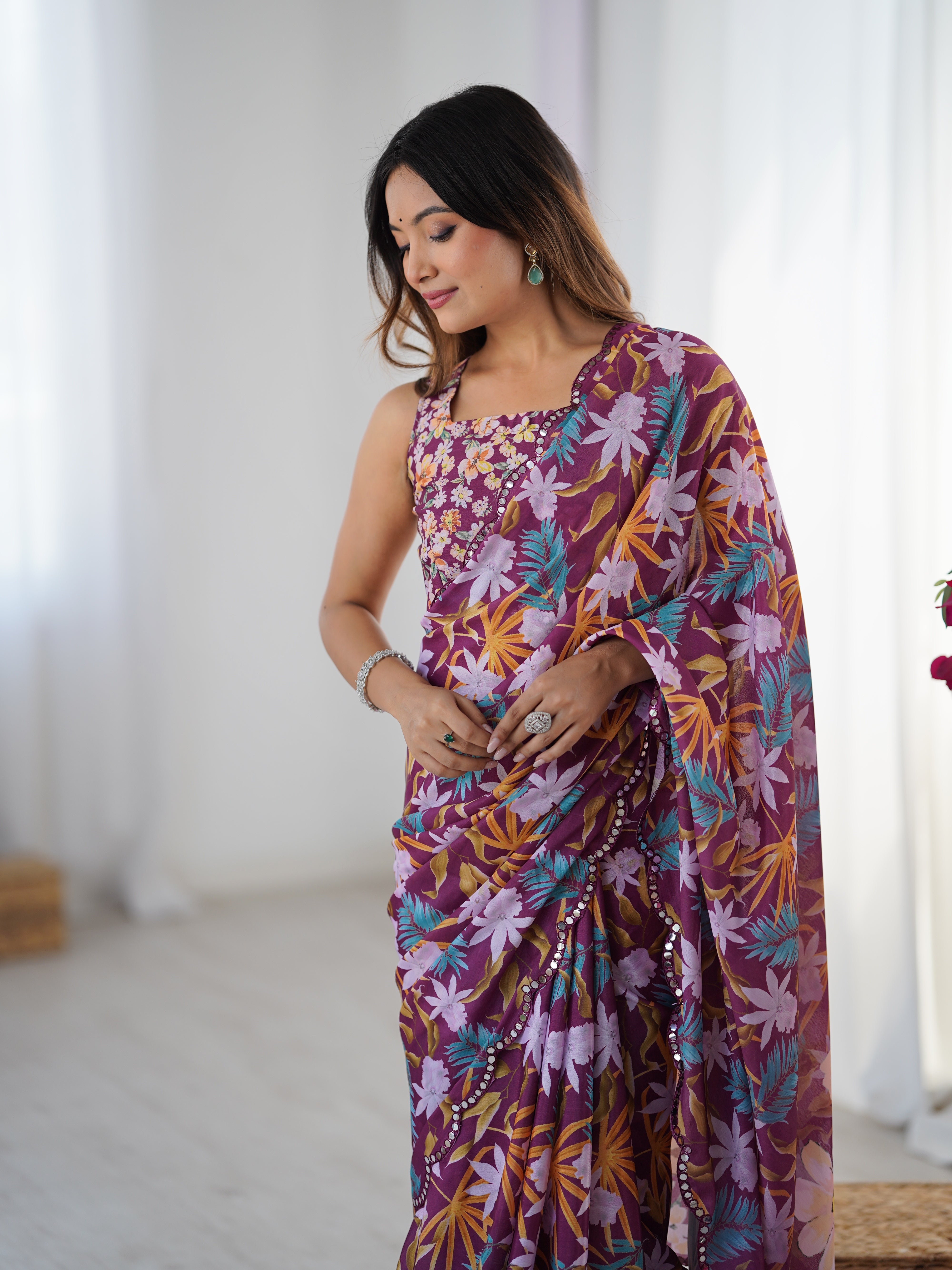 Close-up of a woman in a TRENDBUY floral Chinnon saree, showcasing the intricate print and mirror work border, looking down.