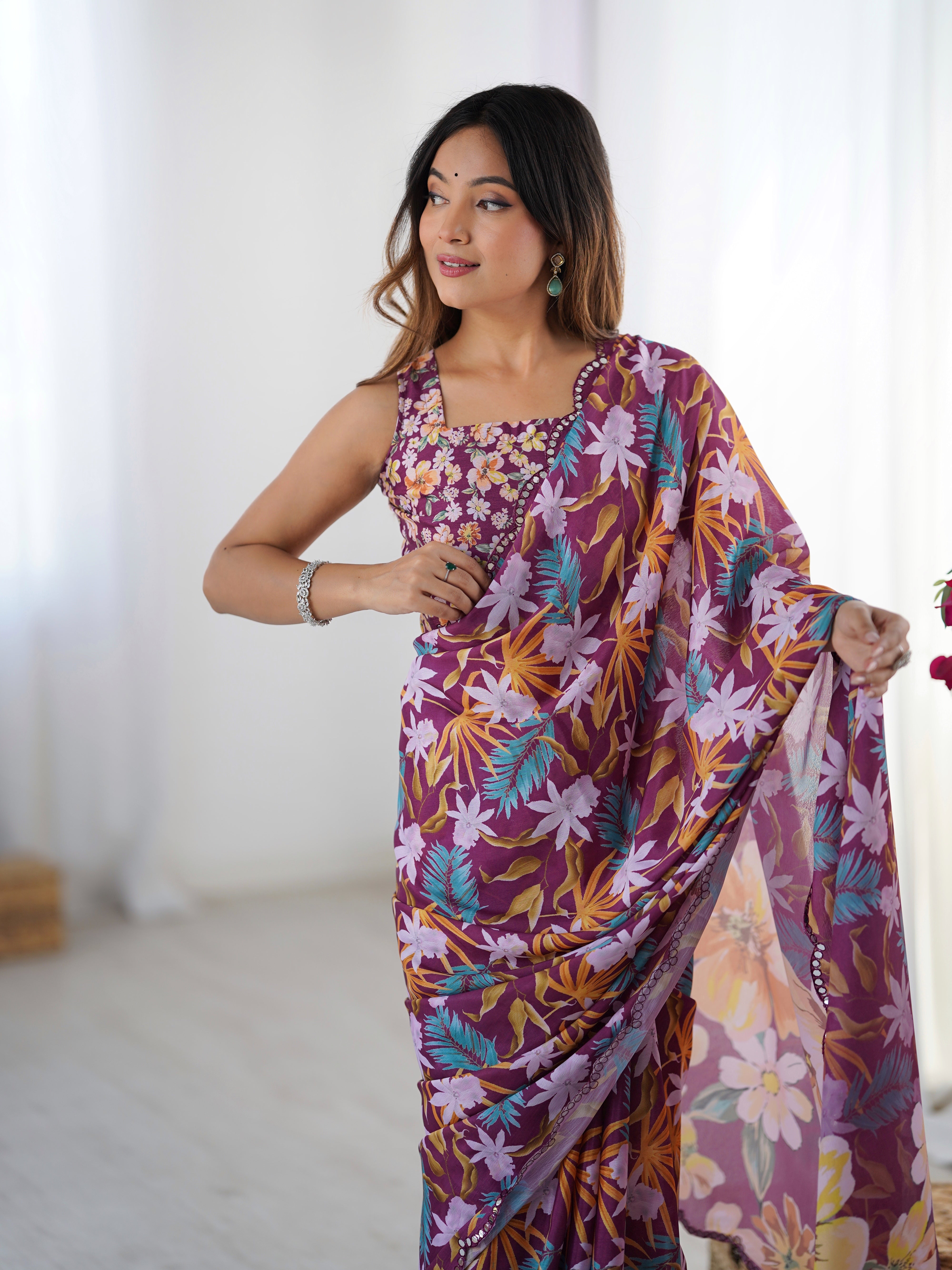 Woman in a vibrant floral heavy Chinnon saree and matching embellished blouse, looking away gracefully.