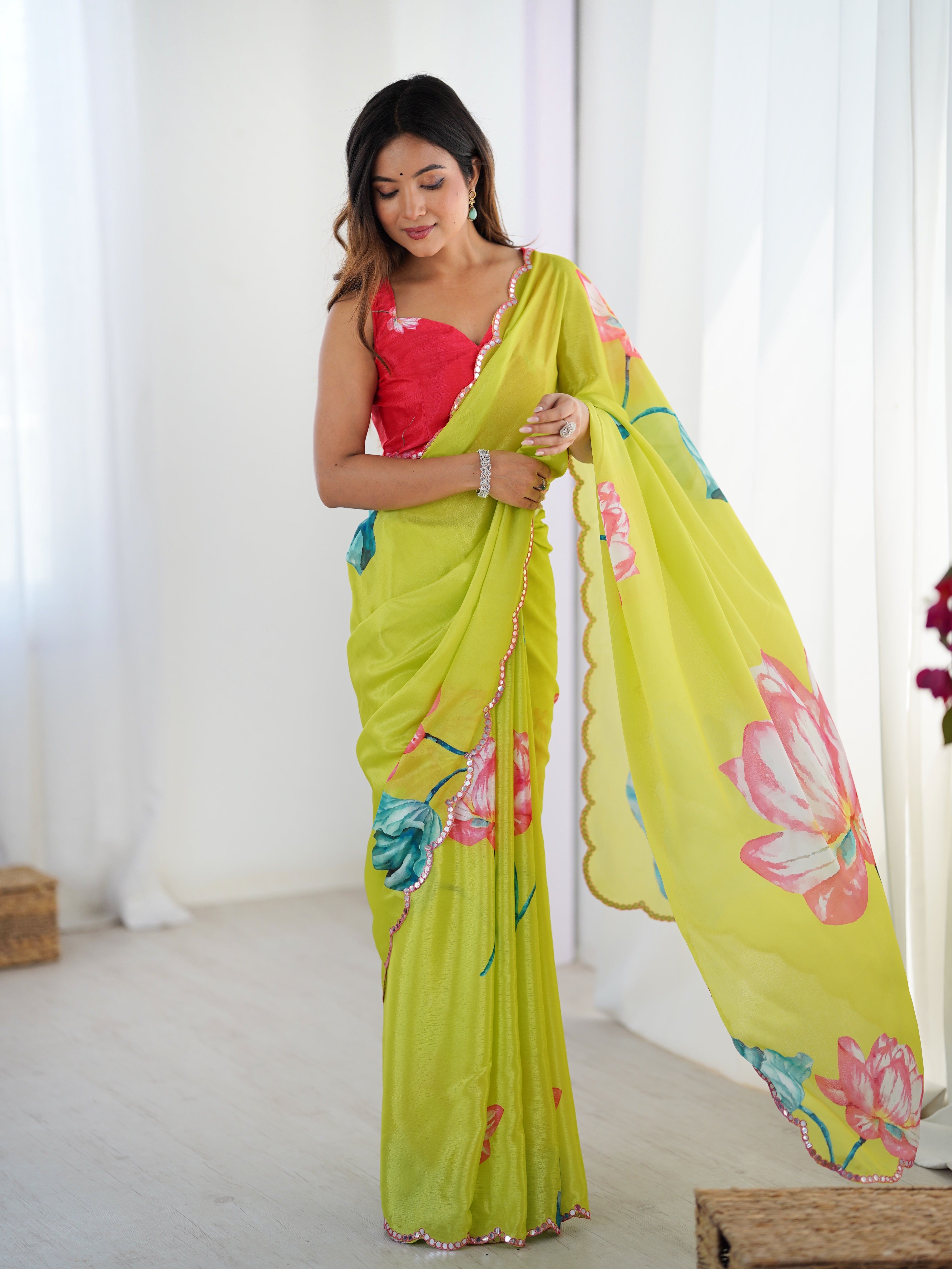 Full shot of model posing in lime green floral Chinnon saree with red blouse and mirror work border.