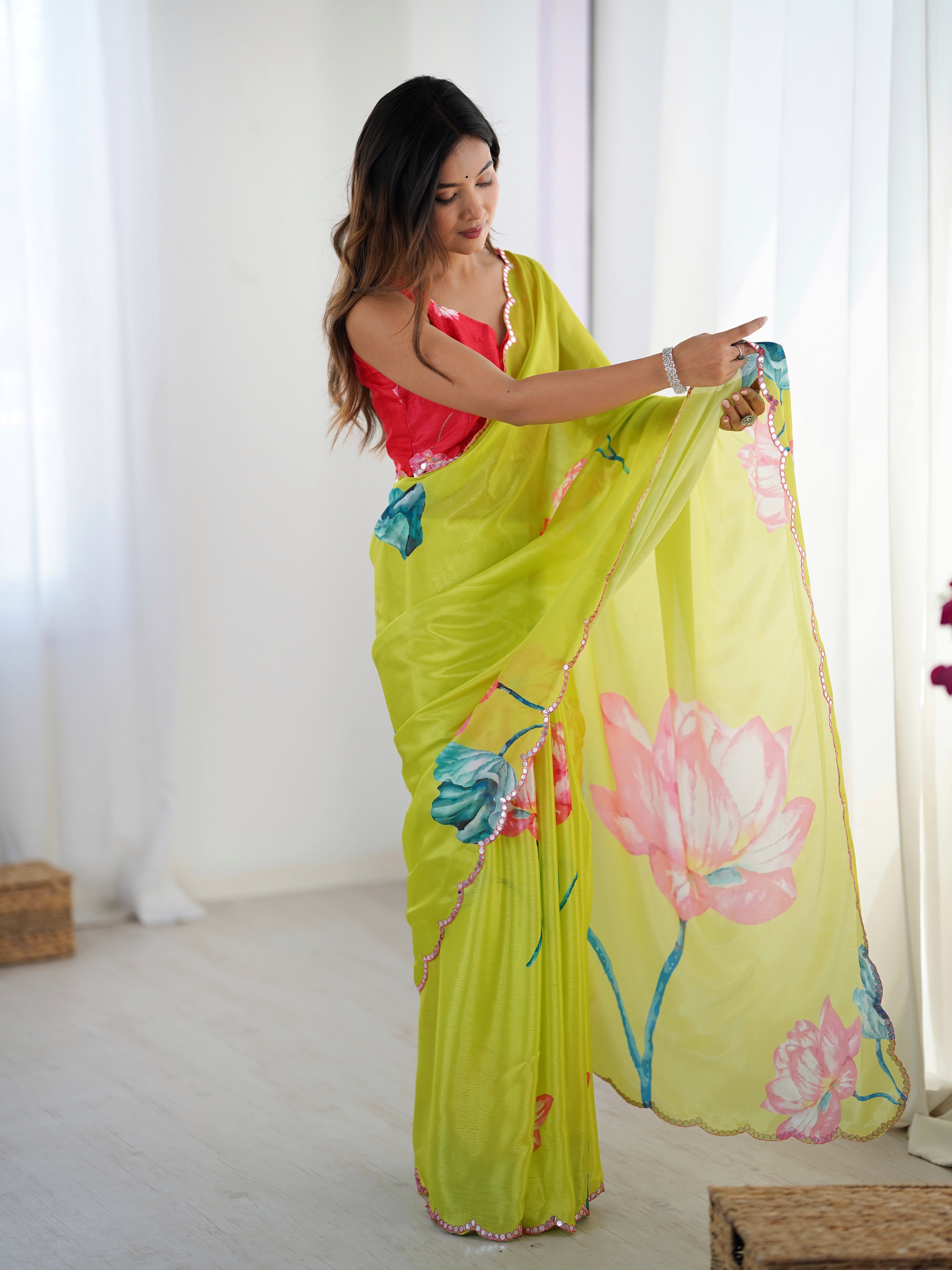 Model adjusting the pallu of her lime green Chinnon saree, showing the large floral patterns.