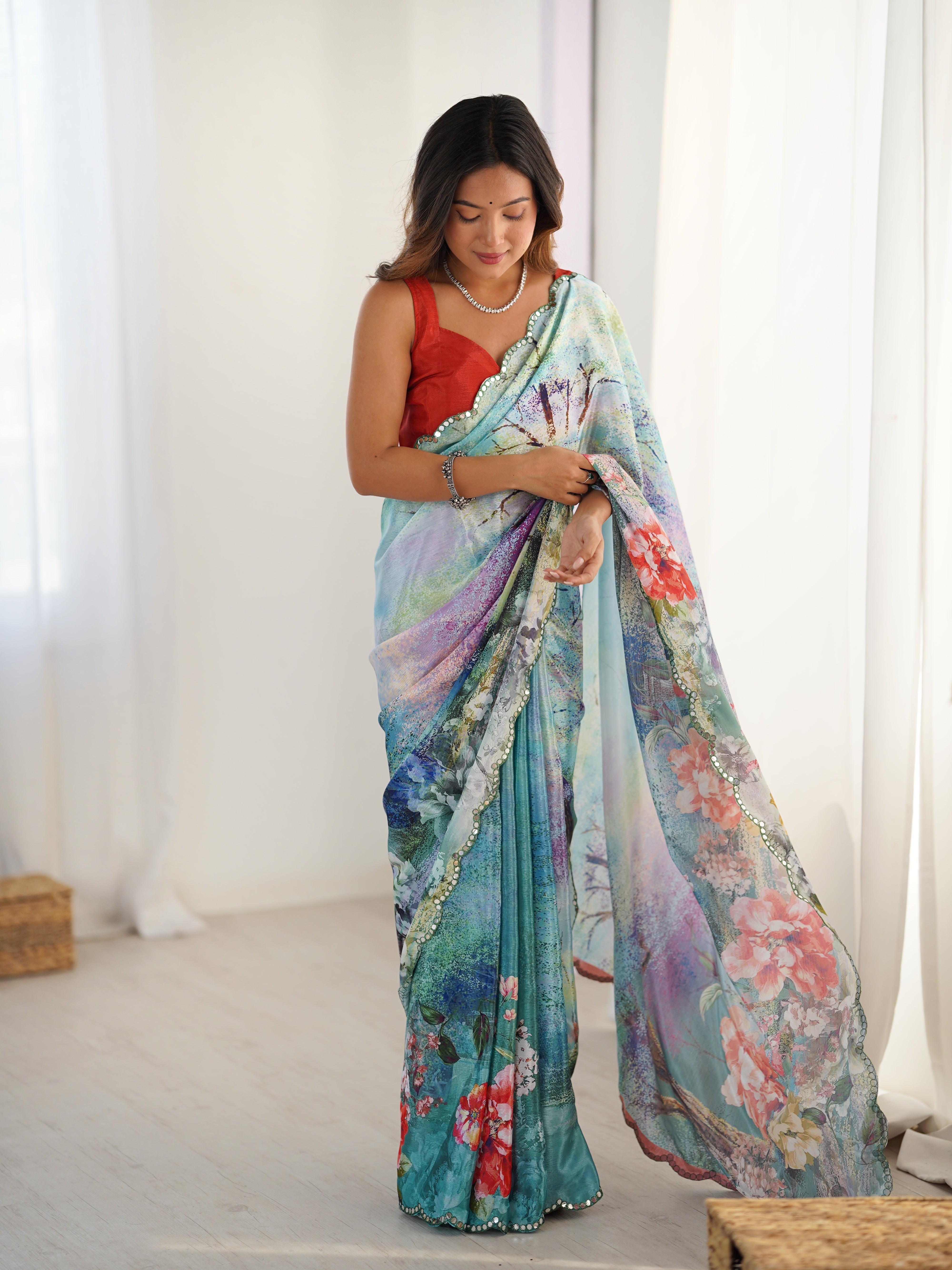 Vibrant print heavy Chinnon saree featuring a detailed Kutchi mirror lace border, draped elegantly.