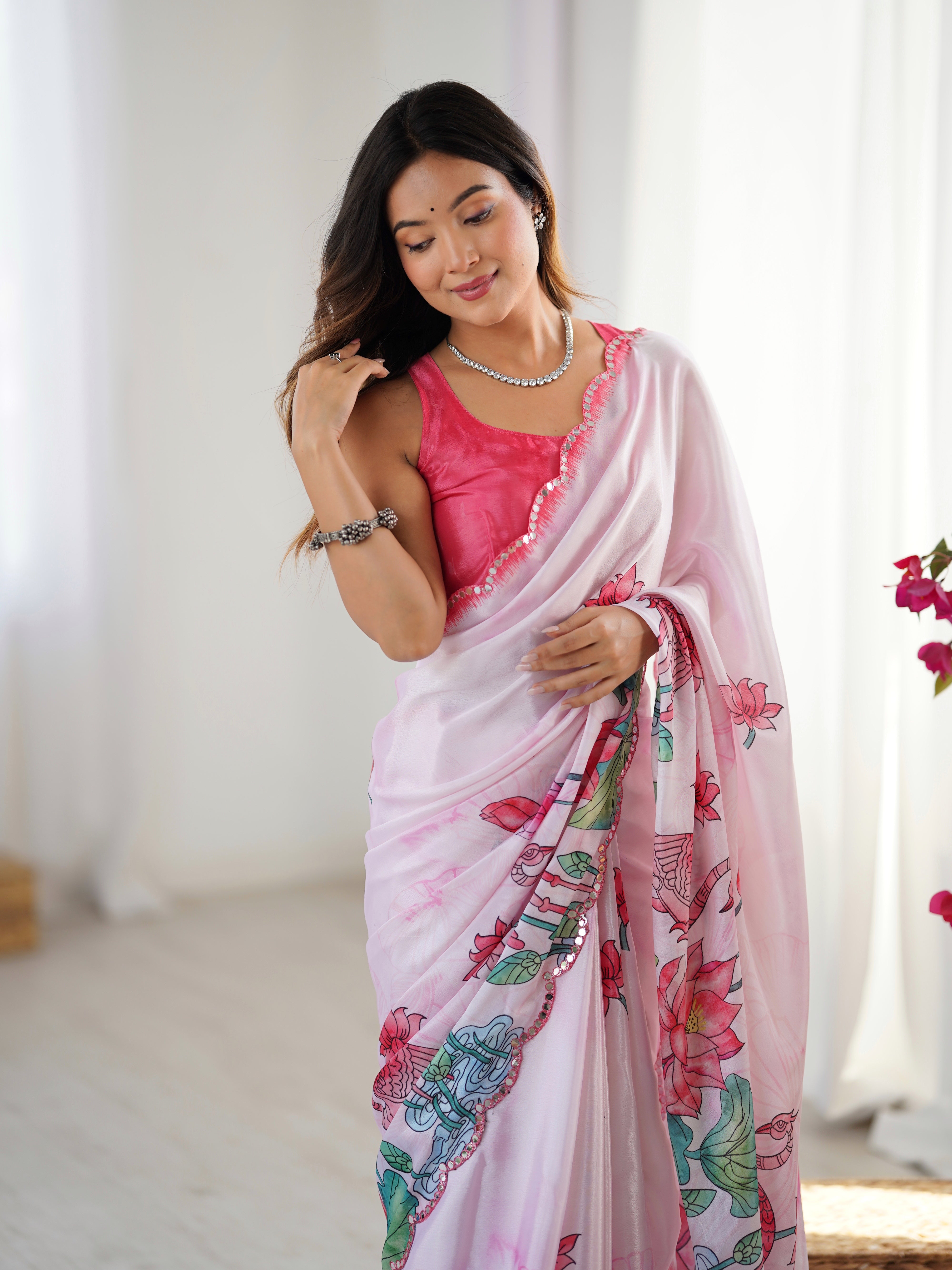 Elegant pink Chinnon saree with vibrant prints and Kutchi mirror work lace border.