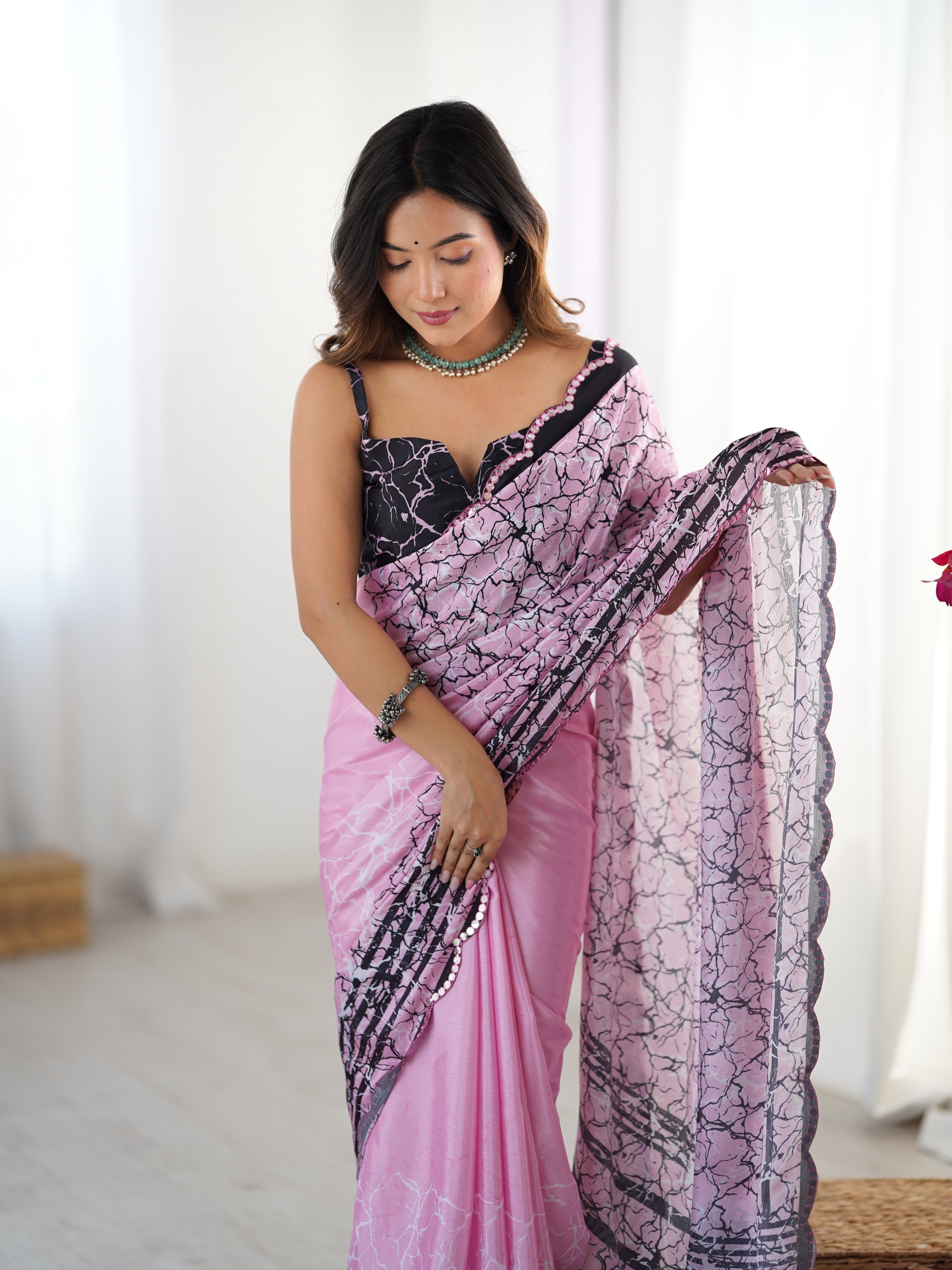 Elegant pink Chinnon saree with black print and Kutchi mirror lace border.