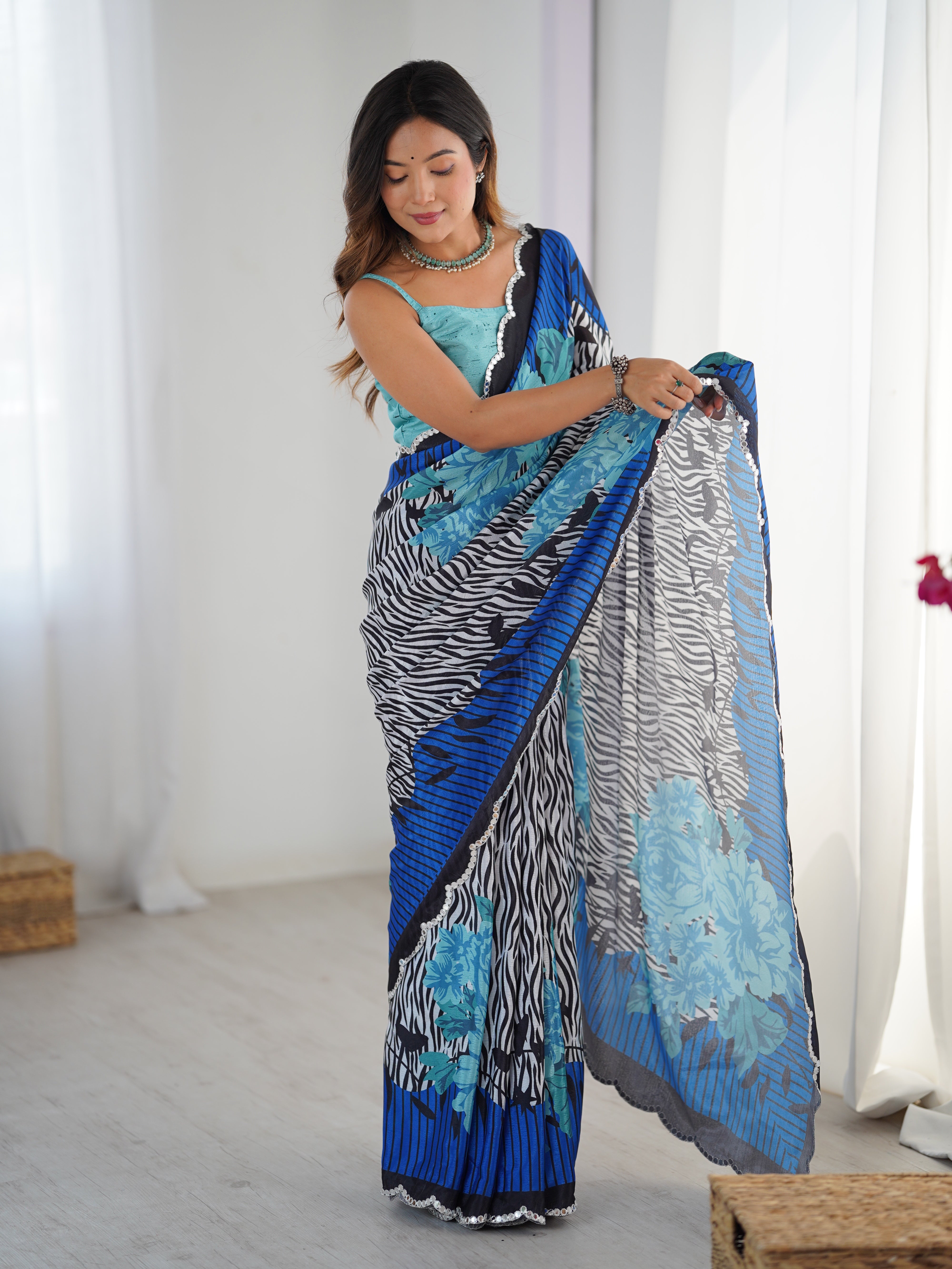 Woman modeling exquisite Chinnon saree with vibrant print and Kutchi mirror lace border.