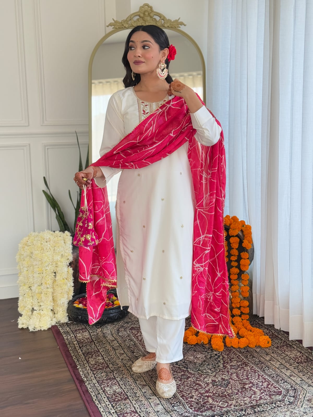 TRENDBUY model holding up the white kurti, pant, and pink dupatta set, presenting the complete ensemble for a stylish occasion.