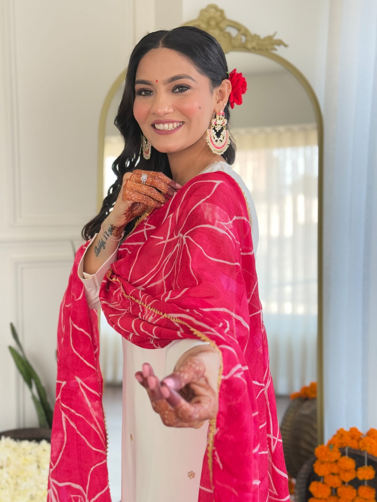 Close-up of a smiling TRENDBUY model wearing a white kurti set and a pink dupatta, showcasing intricate mehndi designs and statement earrings.