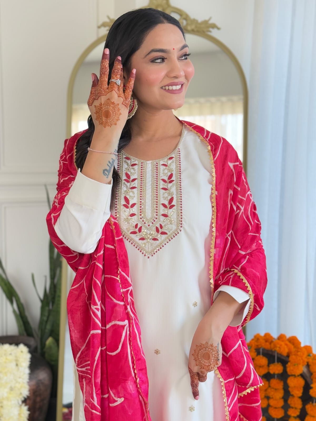 Side view of a TRENDBUY model in white kurti with red embroidery, pink dupatta, and mehndi hands, looking graceful and posing.