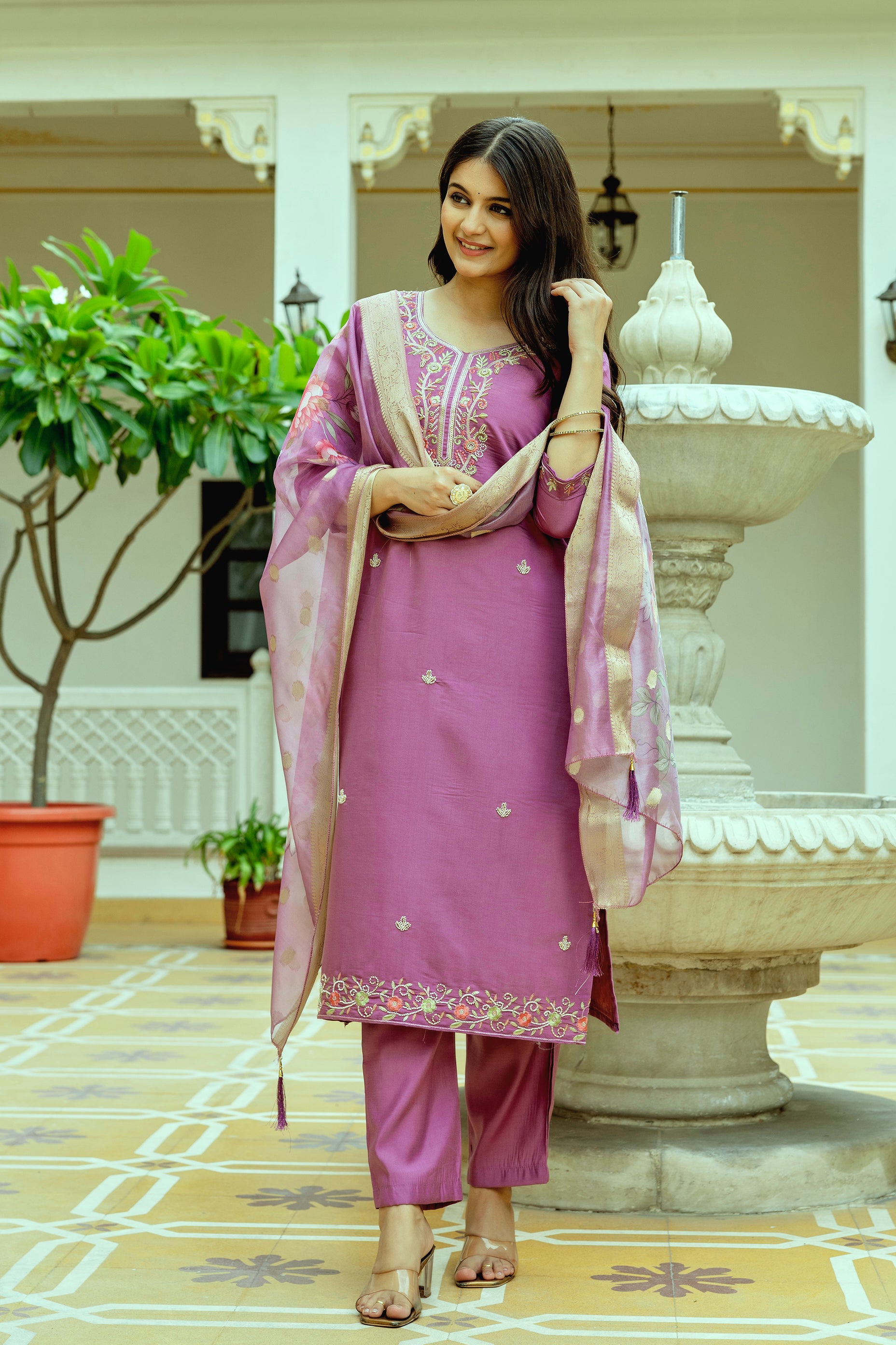 Attractive woman adjusting her hair, highlighting the intricate beadwork and flow of the embroidered violet kurti, pant, and dupatta set from TRENDBUY