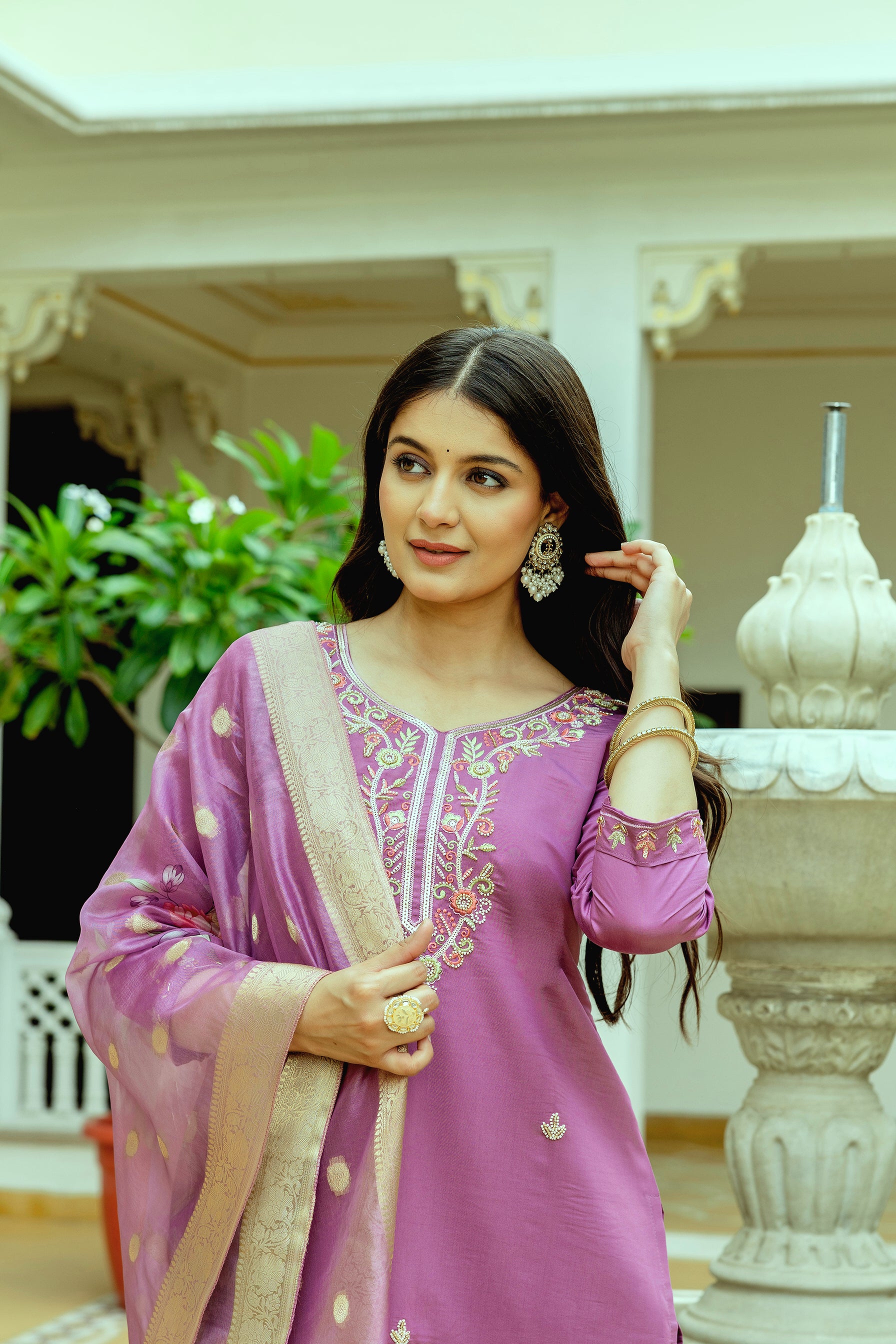 Close-up of a woman's upper body, featuring the exquisite, colorful floral embroidery and bead detailing on the V-neckline of the violet chanderi silk kurti