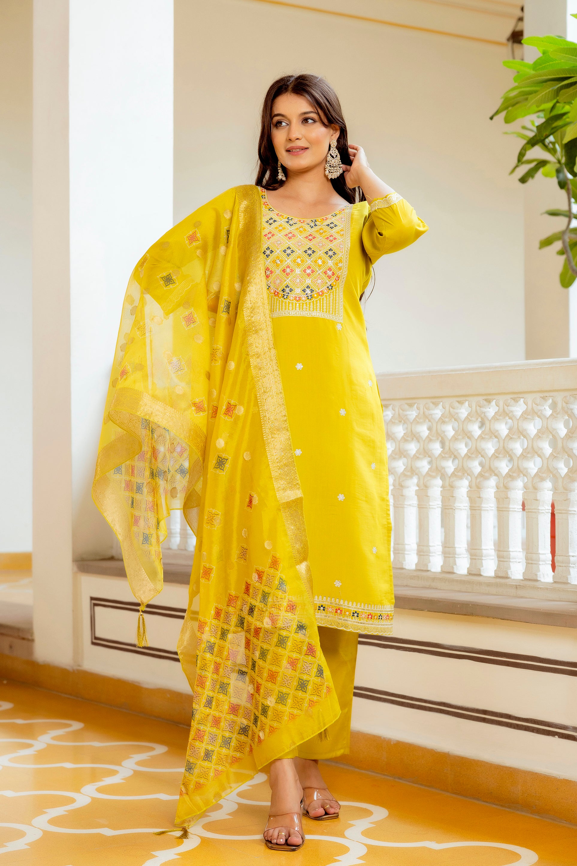 Side profile of the model in the vibrant yellow kurta set, emphasizing the detailed embroidery on the kurti's neckline and the sheer elegance of the dupatta.