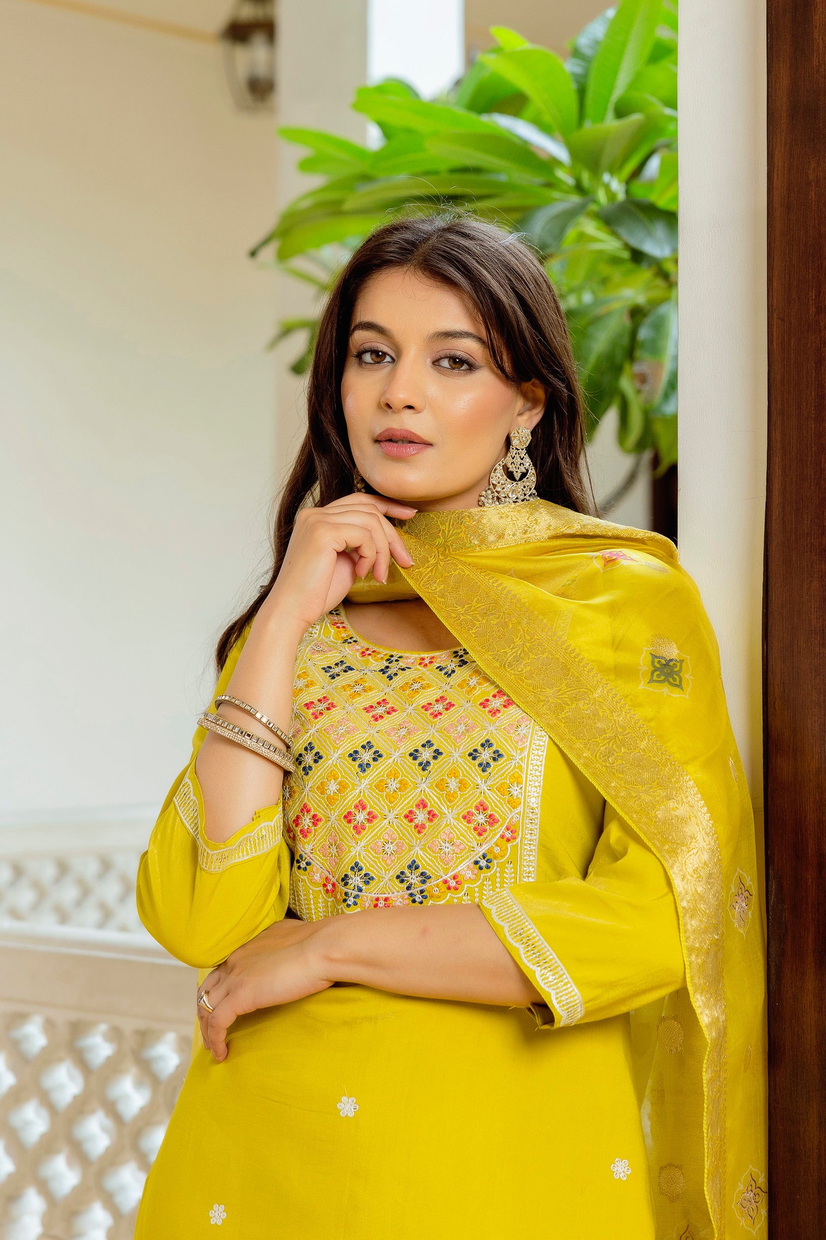 Close-up portrait of the model wearing the yellow kurta set, focusing on her expression and the intricate details of the kurti's embroidery and the dupatta's fabric.
