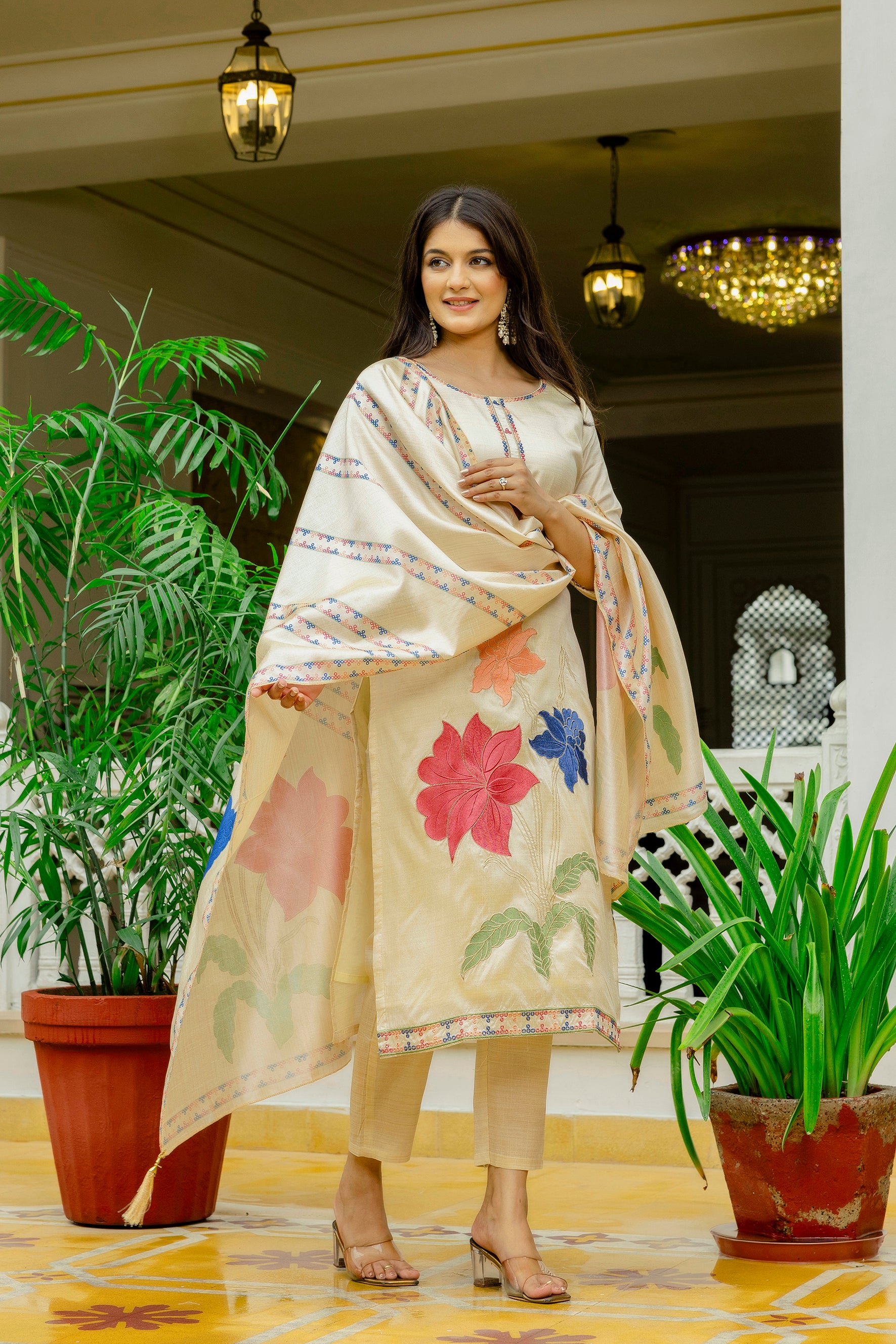 Model in a full-length shot showcasing the beige Viscose Assam Silk Kurta Set with vibrant floral embroidery on the kurta and dupatta, posing outdoors.