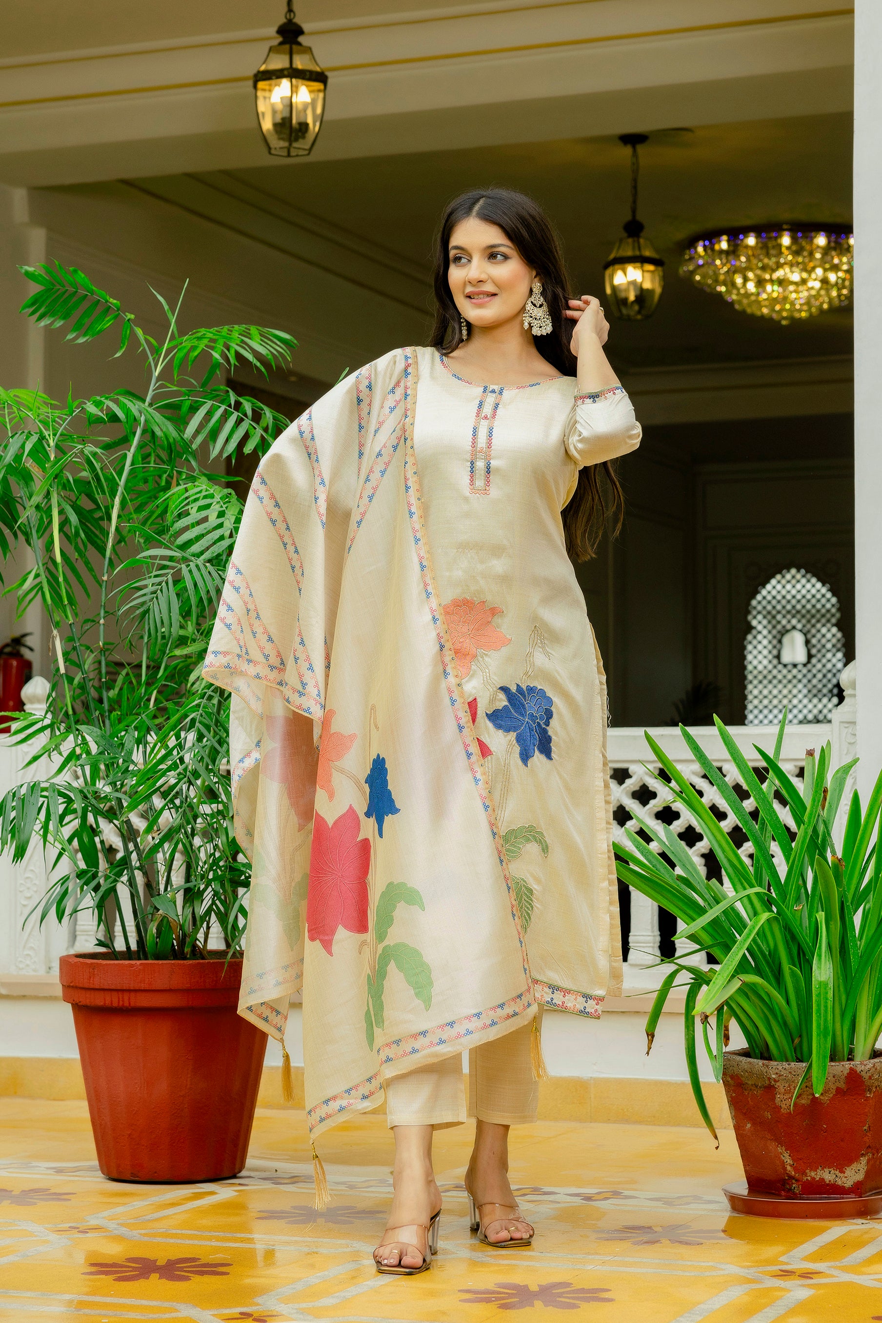 Elegant model adjusting her hair, displaying the complete beige ethnic wear ensemble, highlighting the flow and design of the embroidered dupatta.