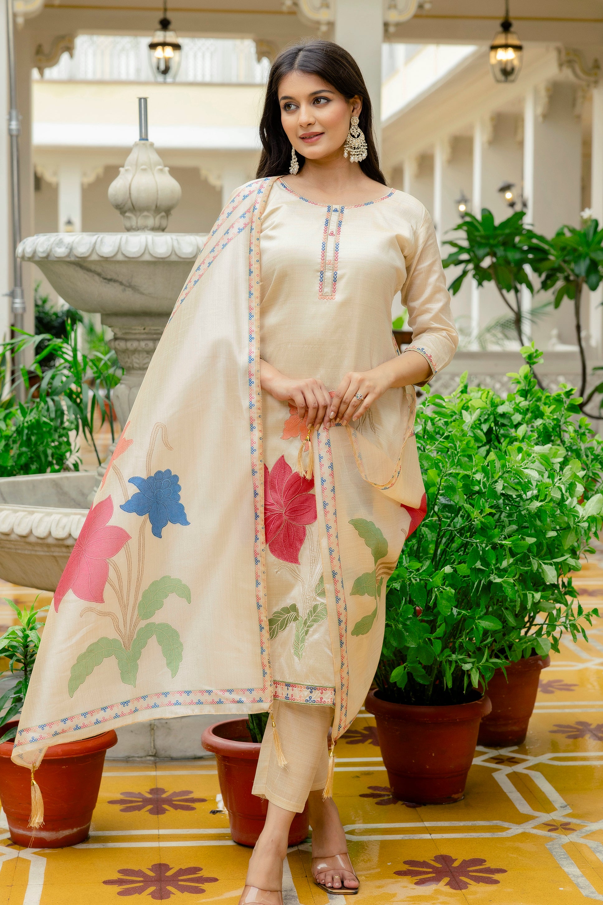 Full body shot of the model in the beige kurta set, standing gracefully near a decorative fountain, emphasizing the outfit's overall aesthetic.