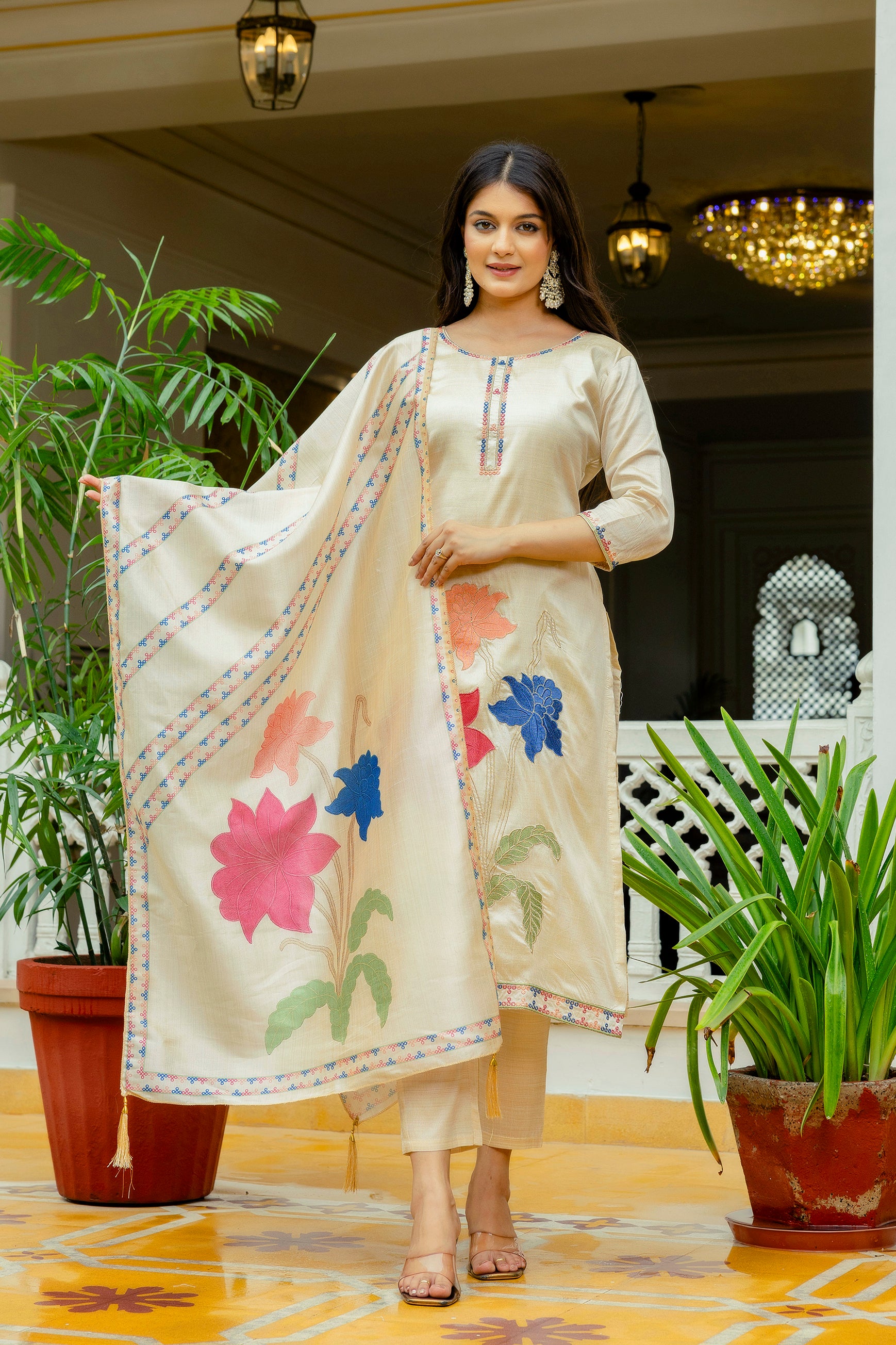 Model gracefully holding out the richly embroidered dupatta, highlighting the colorful floral patterns against the beige silk fabric.