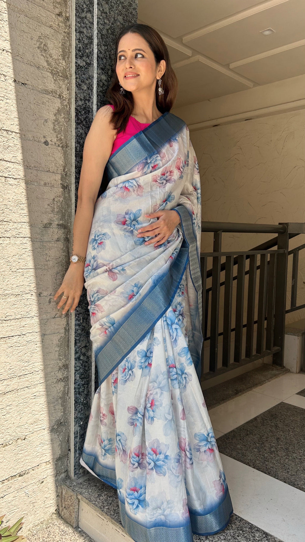White saree with a contrasting blue border, showcasing the fabric's soft texture and elegant drape.