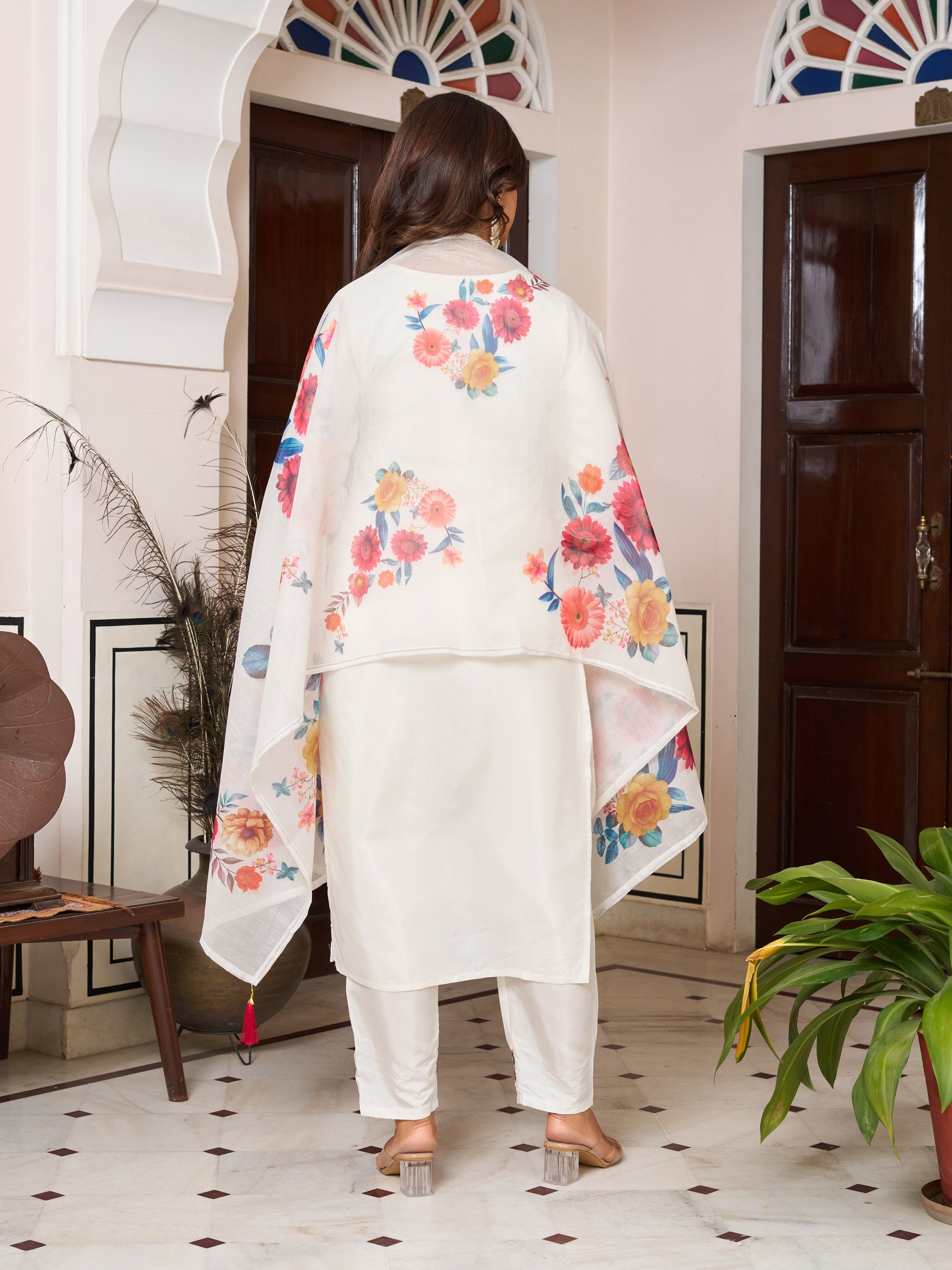 Back view of a woman in an elegant white Chanderi silk kurta set with a vibrant floral dupatta.