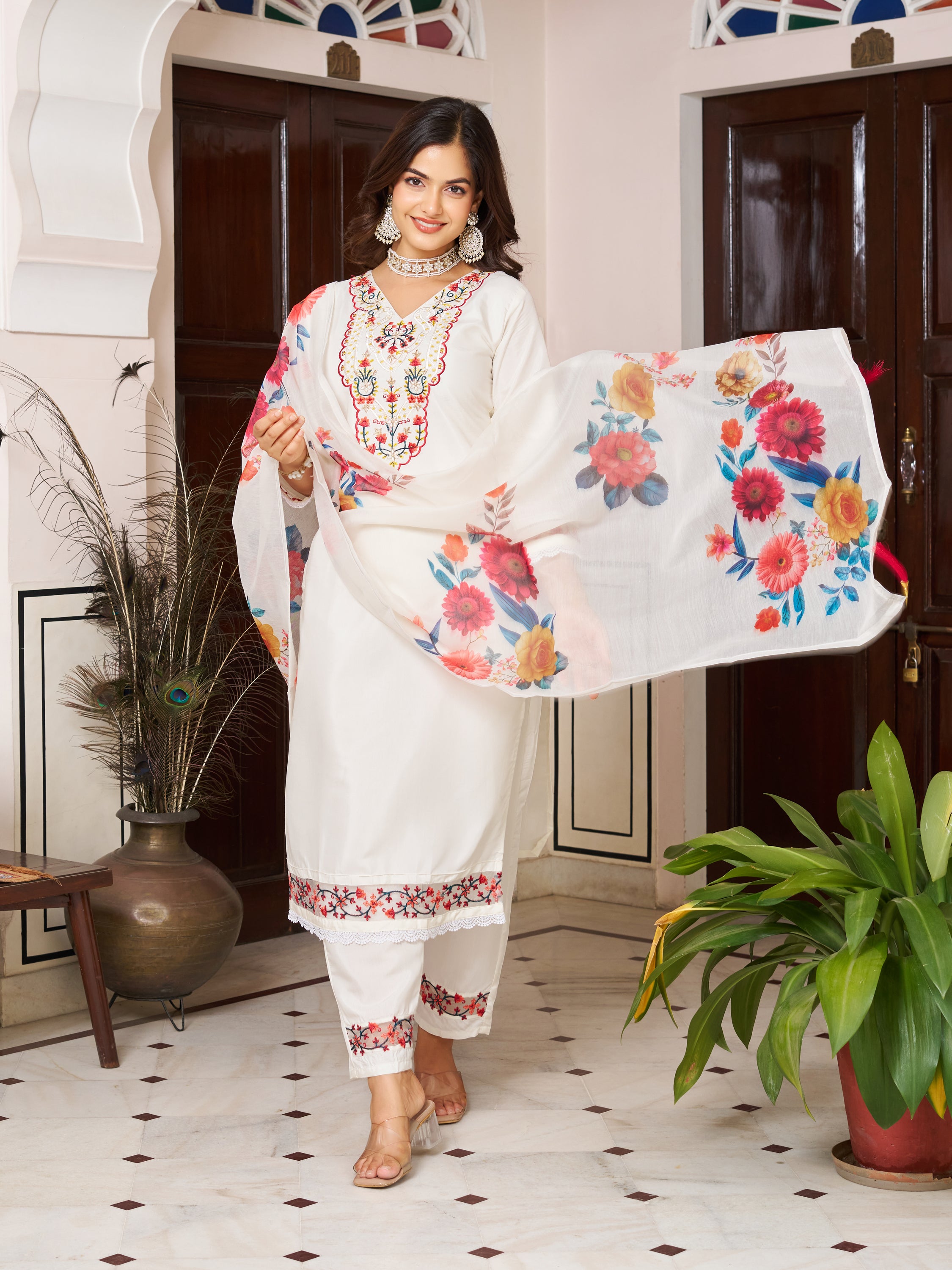 Woman walking cheerfully in a white embroidered Chanderi silk kurta set with a vibrant floral dupatta.